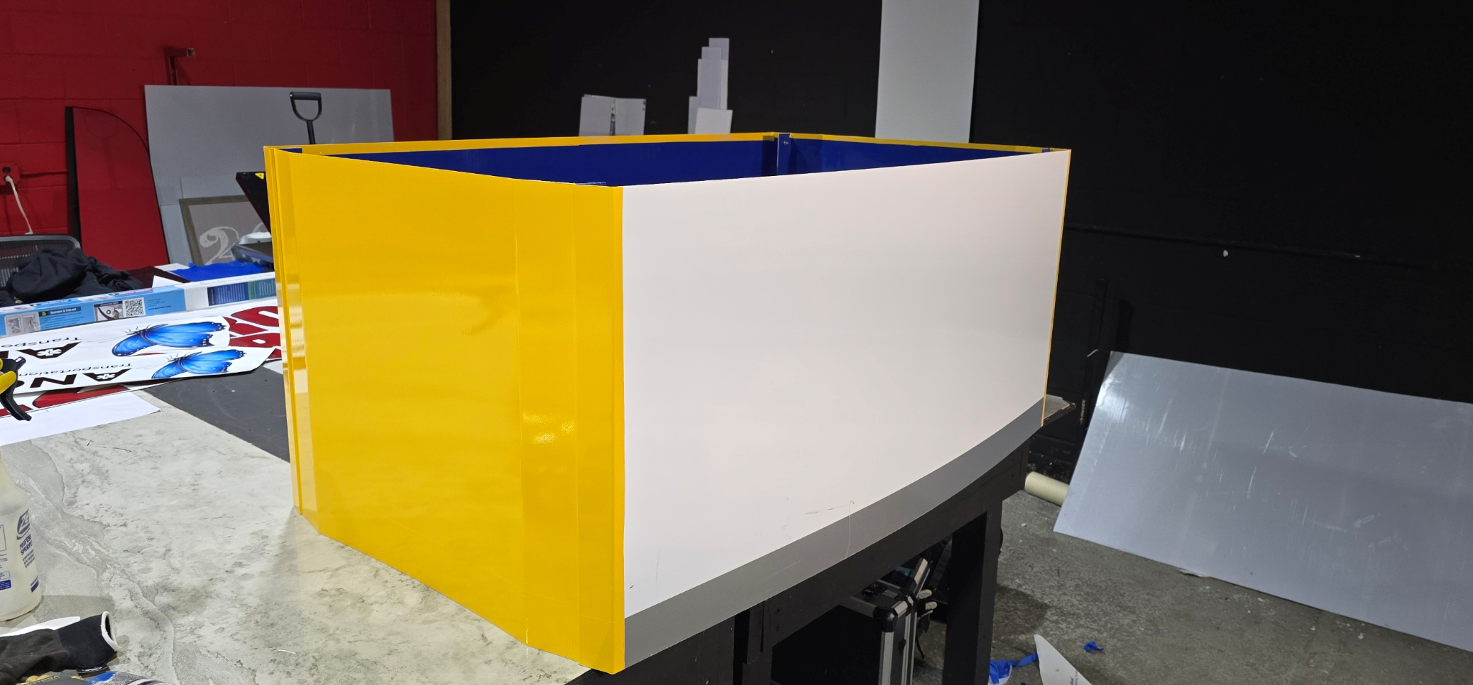 A yellow, white, and blue box being assembled on a work table in a workshop.