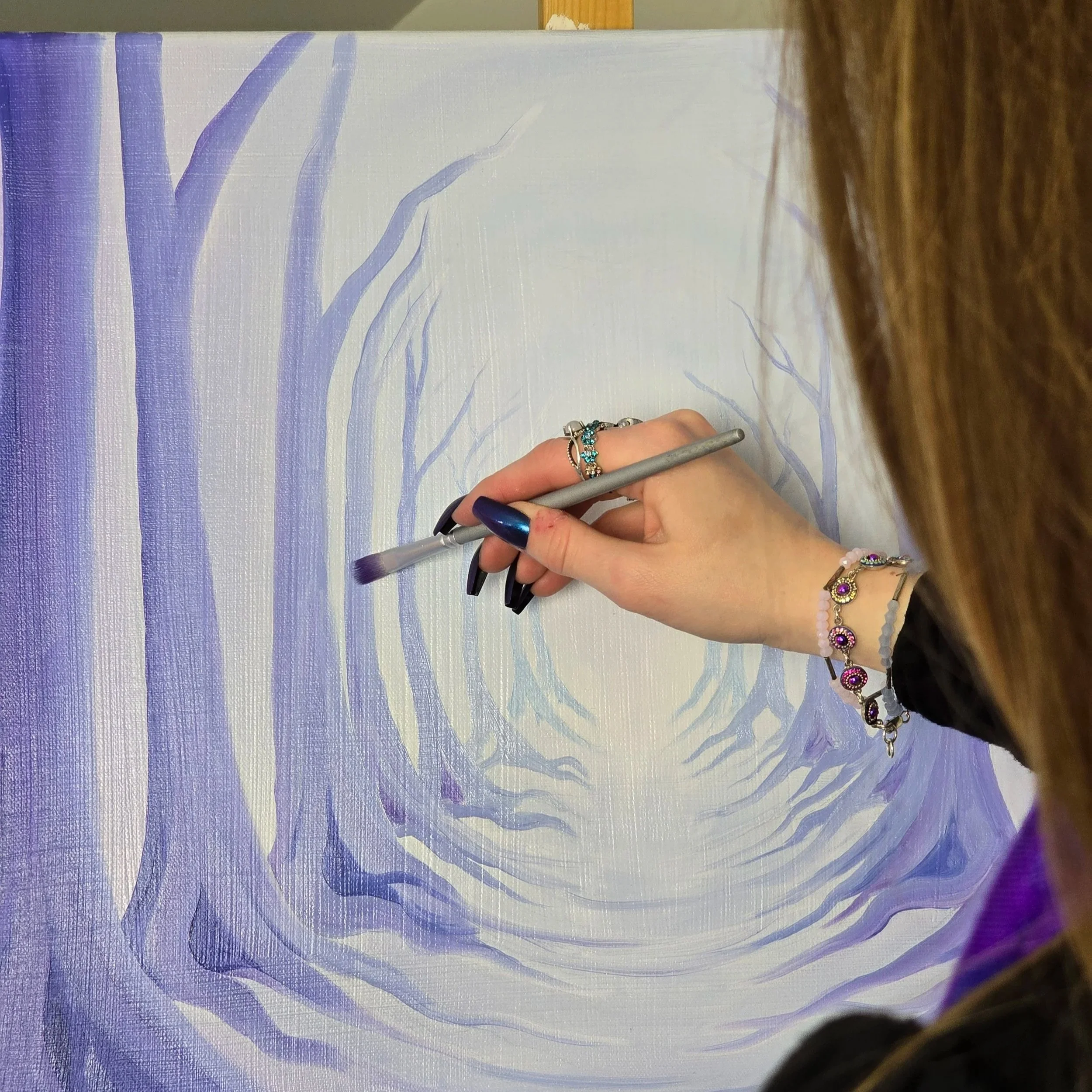 Artist painting on a canvas with shades of blue and purple, depicting abstract tree-like artwork. Support small businesses in Manitoba Canada, local artists in Manitoba, women owned small businesses, support local artists, small business owner