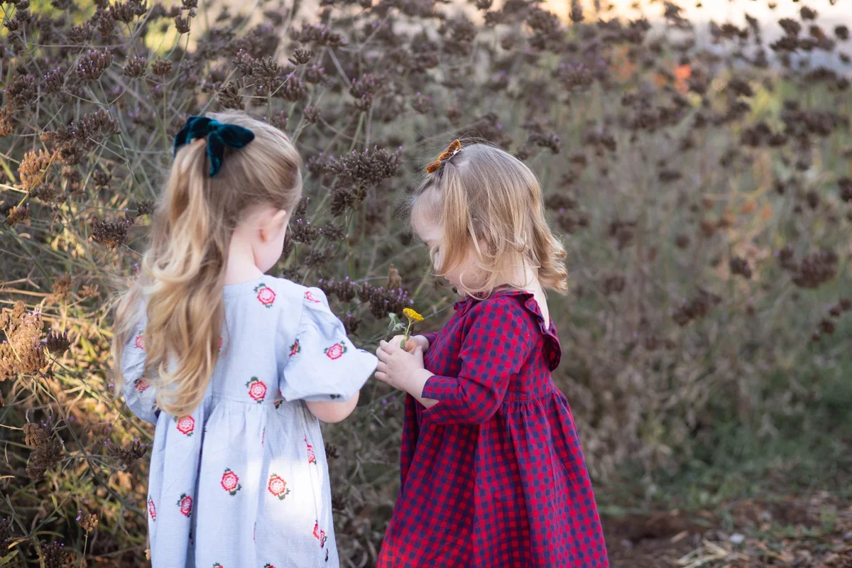 young kids in photo session outside in nature looking at flowers