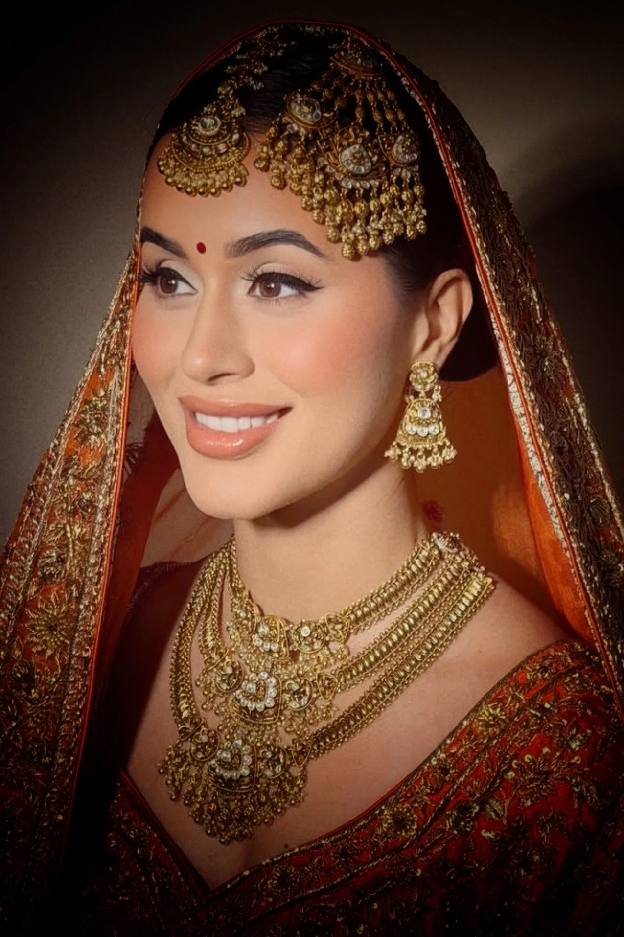 Indian bride wearing layered gold bridal necklaces and traditional jewelry styled for wedding ceremony.
