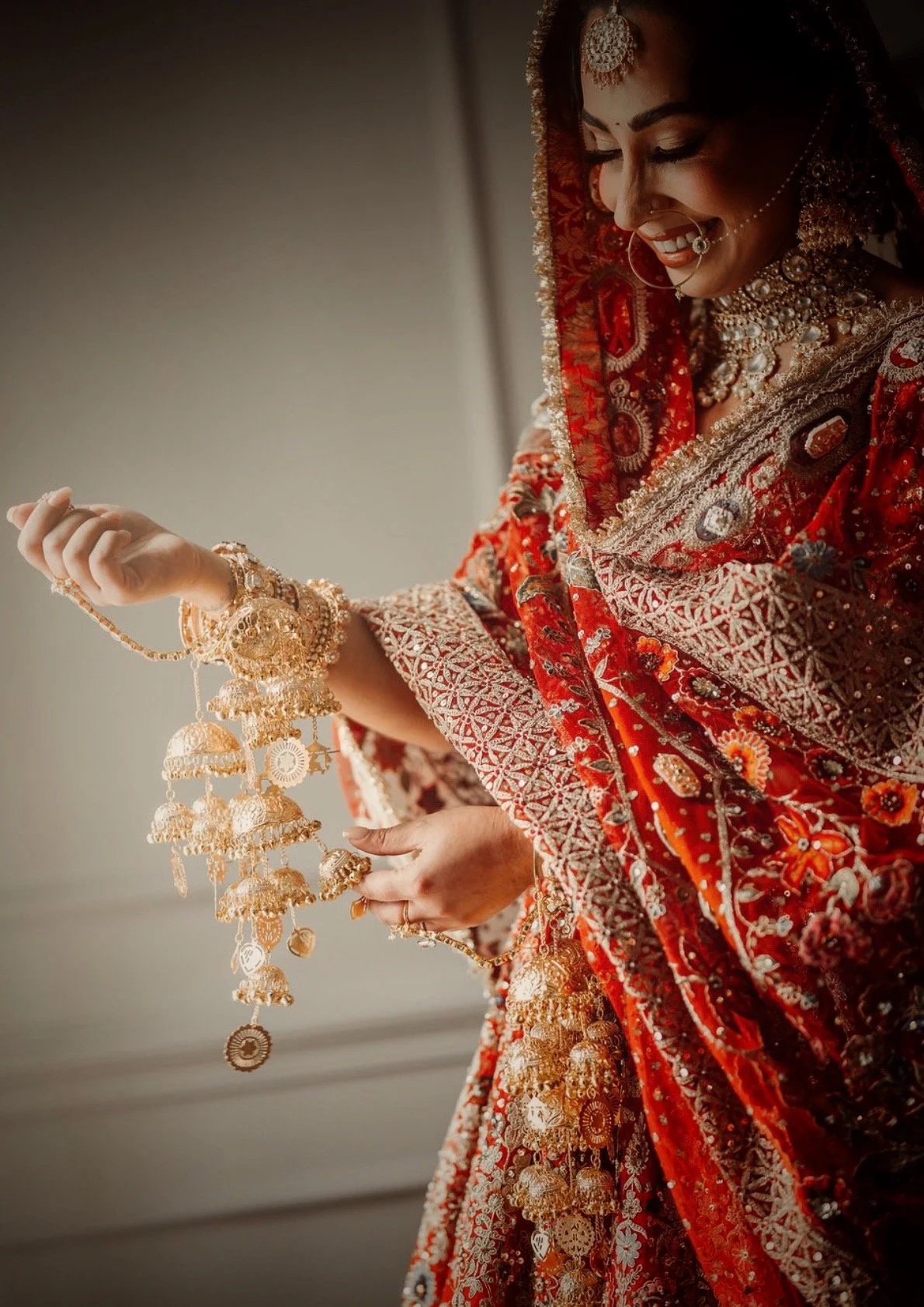 Indian bride wearing choora and holding kaleeray with red bridal lehenga during pre-wedding ceremony.