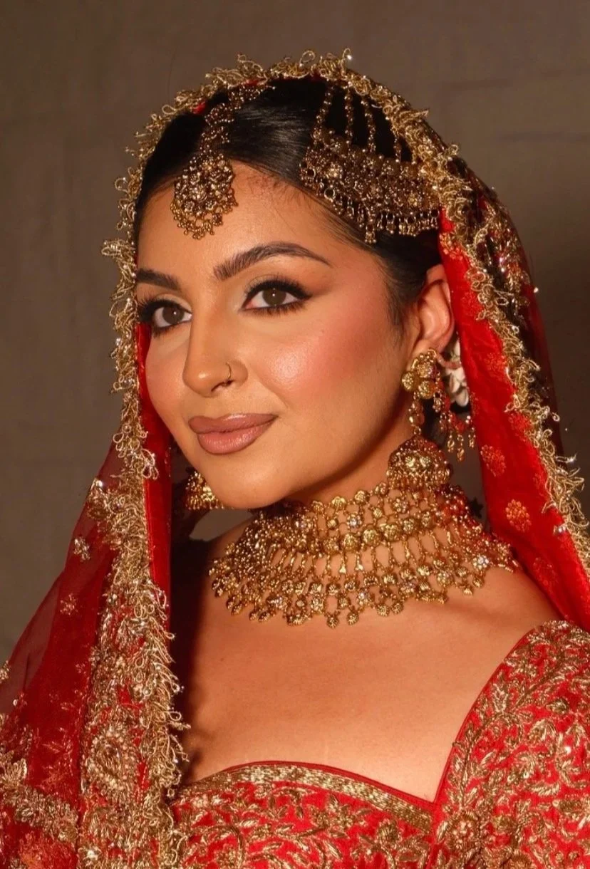 Indian bride wearing gold kundan choker necklace with red bridal lehenga and traditional head jewelry.