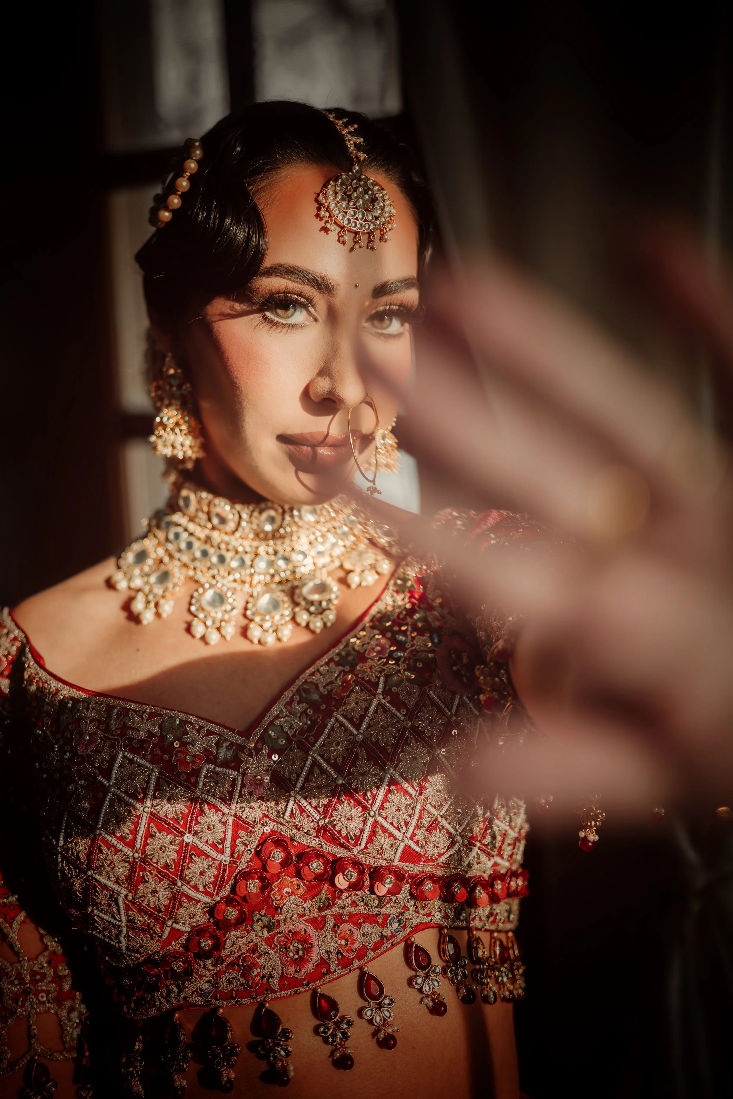 Indian bride wearing kundan choker necklace and bridal jewelry styled with red lehenga for wedding ceremony.