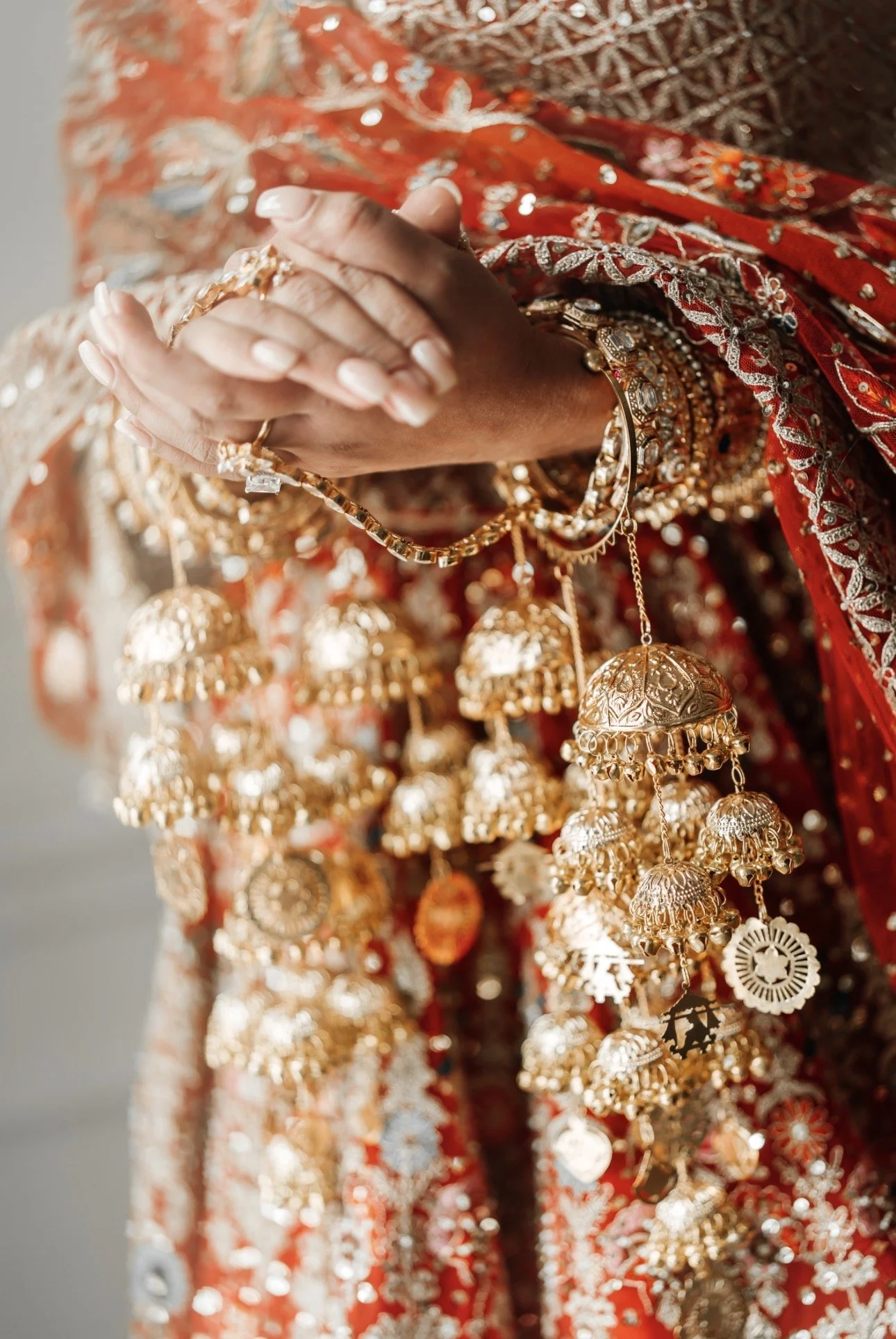 Close-up of bride’s hands wearing choora bangles and kaleeray during traditional pre-wedding ritual.