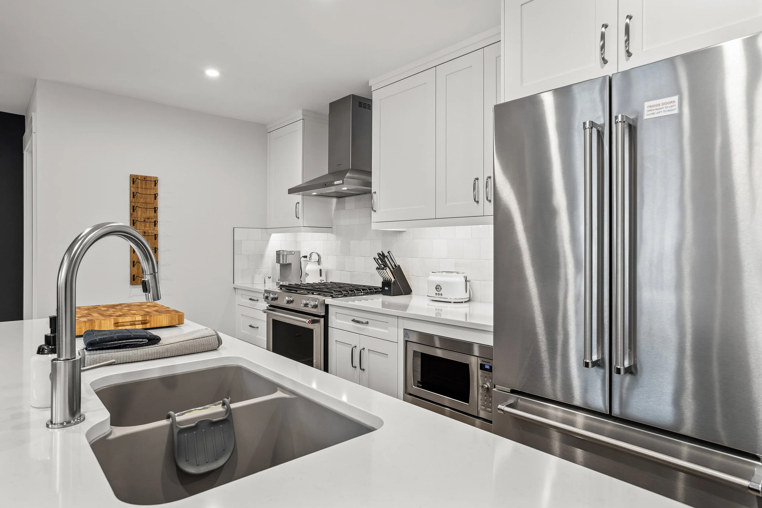 Modern kitchen with stainless steel appliances, white cabinetry, and a kitchen island with a built-in sink.