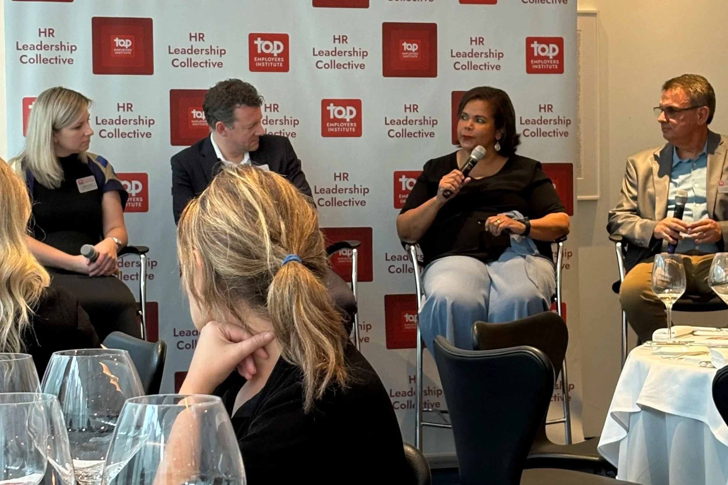 Four people on a panel at an HR leadership collective event, sitting on chairs in front of a backdrop with the 'Top Employers Institute' logo and text.