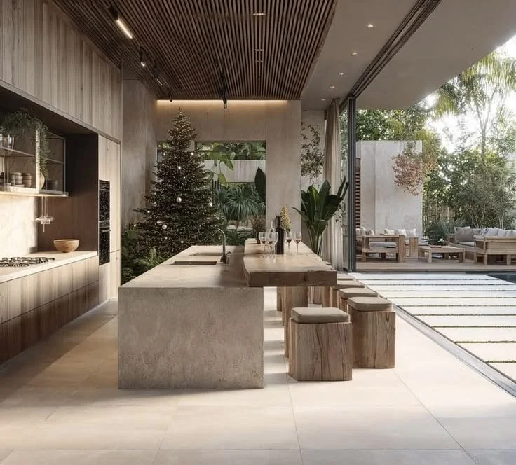 Modern kitchen with Christmas tree, open outdoor seating area with sofas, and large glass windows.