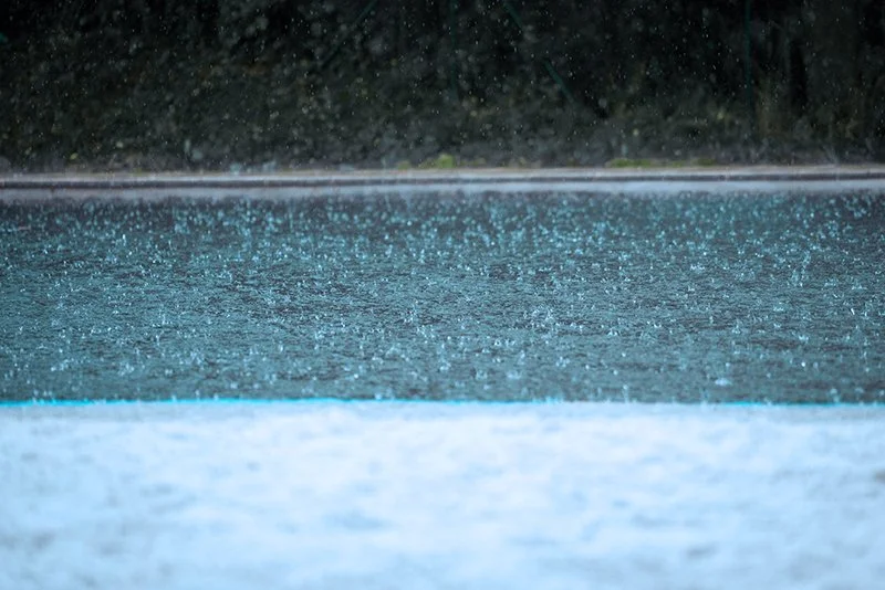 Heavy rain falling on a backyard pool during a Florida storm