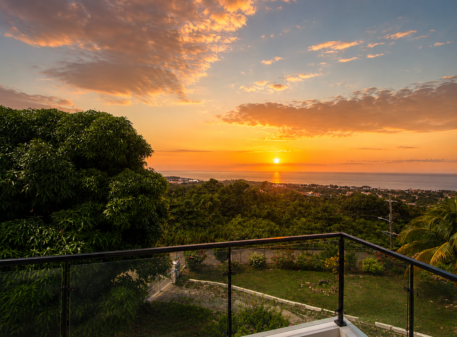 A swimming pool on a hilltop with a view of lush green hills, a coastal town, and the ocean in the distance