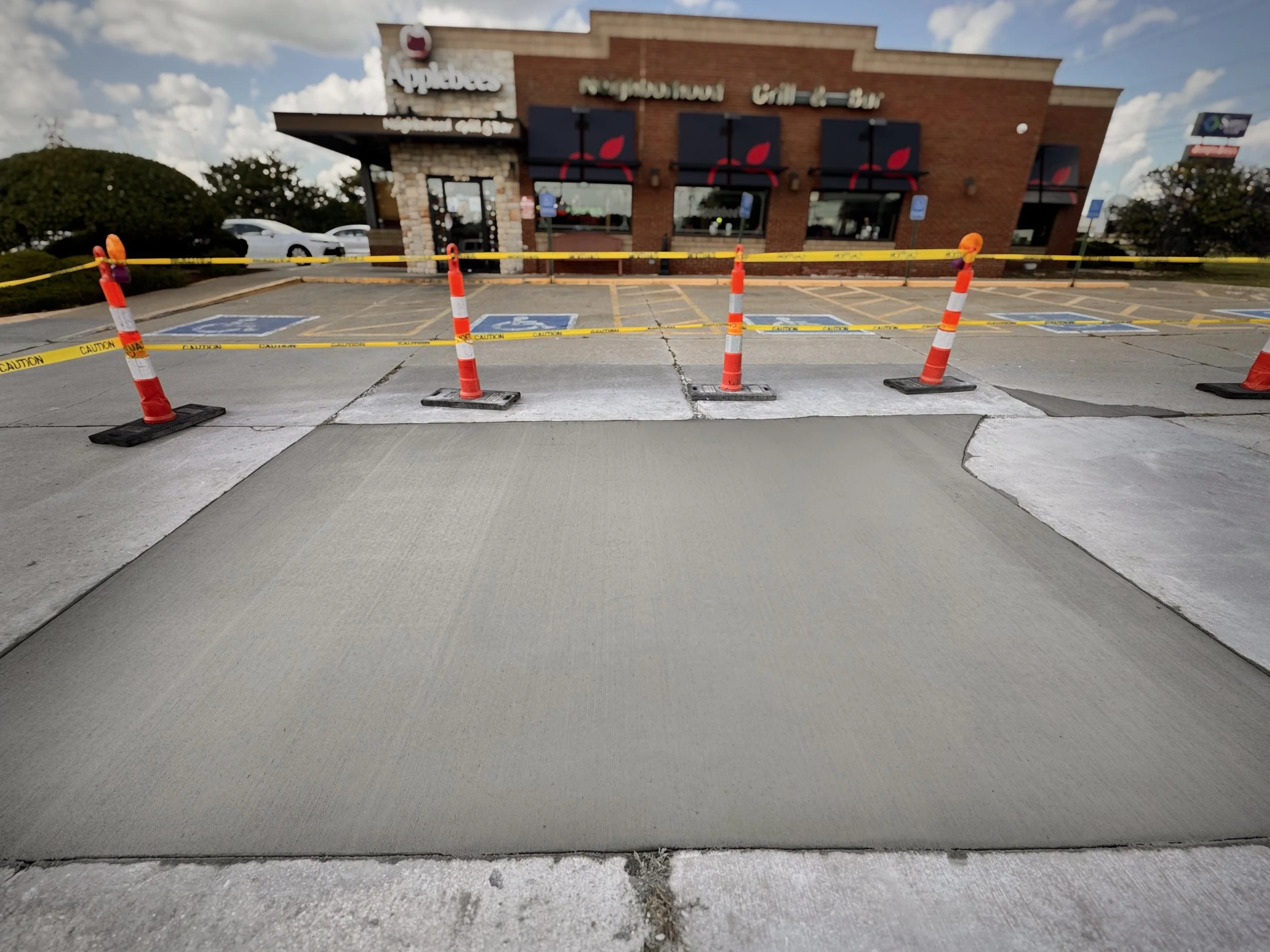 Empty parking lot with caution tape and cones in front of a restaurant, with parking spaces marked for handicapped parking nearby.