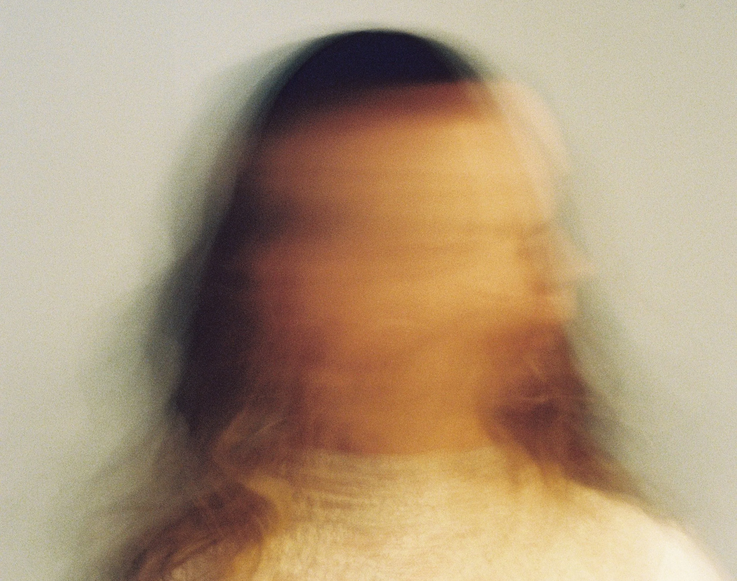 Very close-up, blurry photograph of a person's forehead, eyebrow, and part of the hairline.