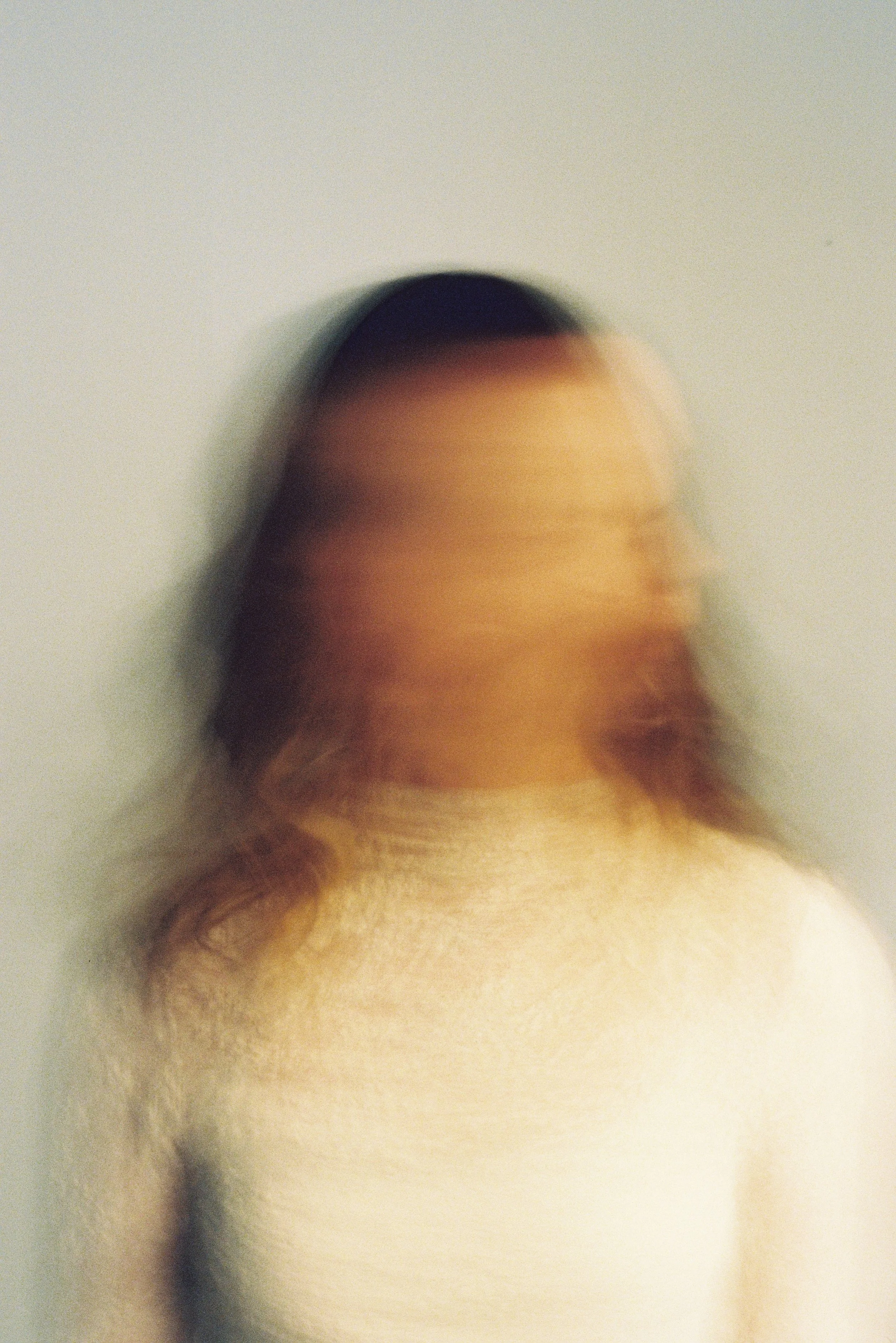 An abstract, blurry image of a person's head and shoulders, with the person's face and features indistinct.