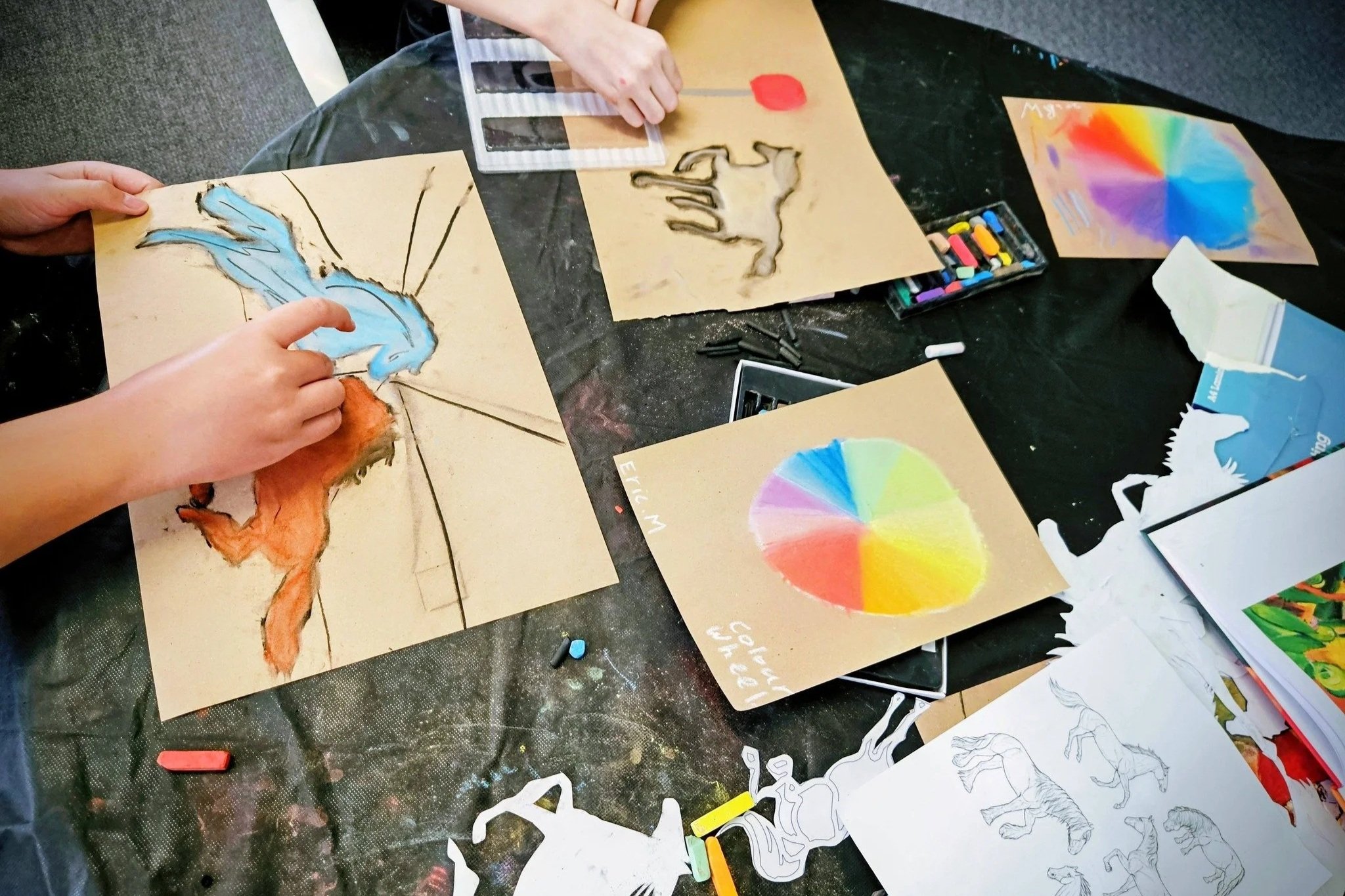 Children's hands making art - colourful horses and colour wheels