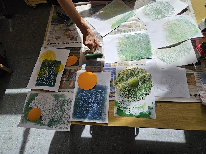 A table strewn with a variety of prints in progess