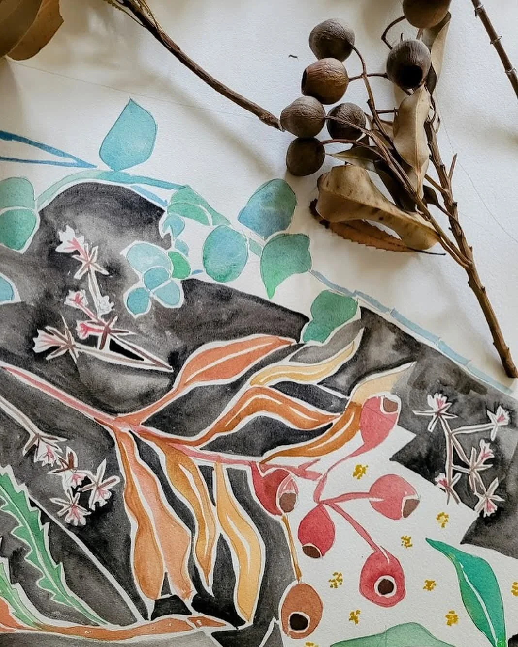 Mixed media artwork featuring various botanical elements including leaves, berries, and flowers in watercolor style, with a branch of dried berries and leaves placed on top.