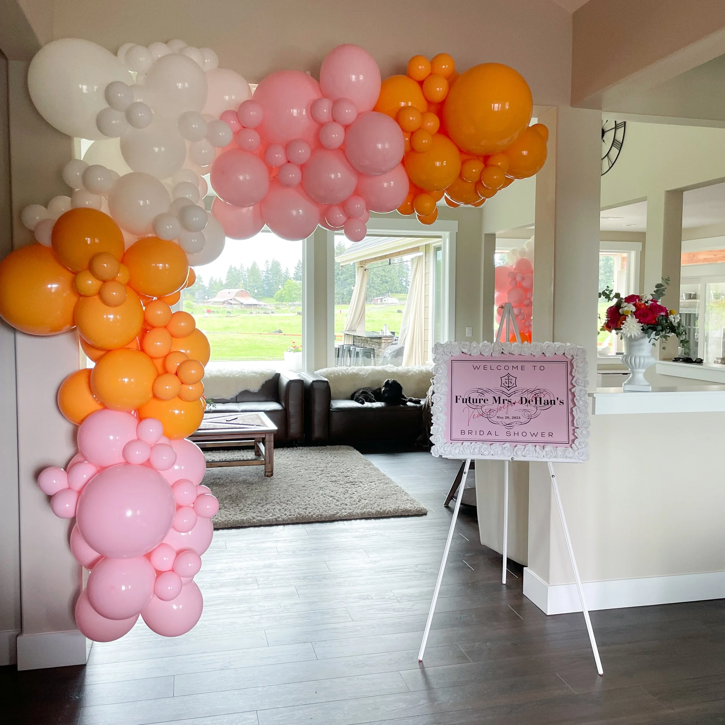 Balloon arch with pink, white, and orange balloons at a bridal shower decorated area