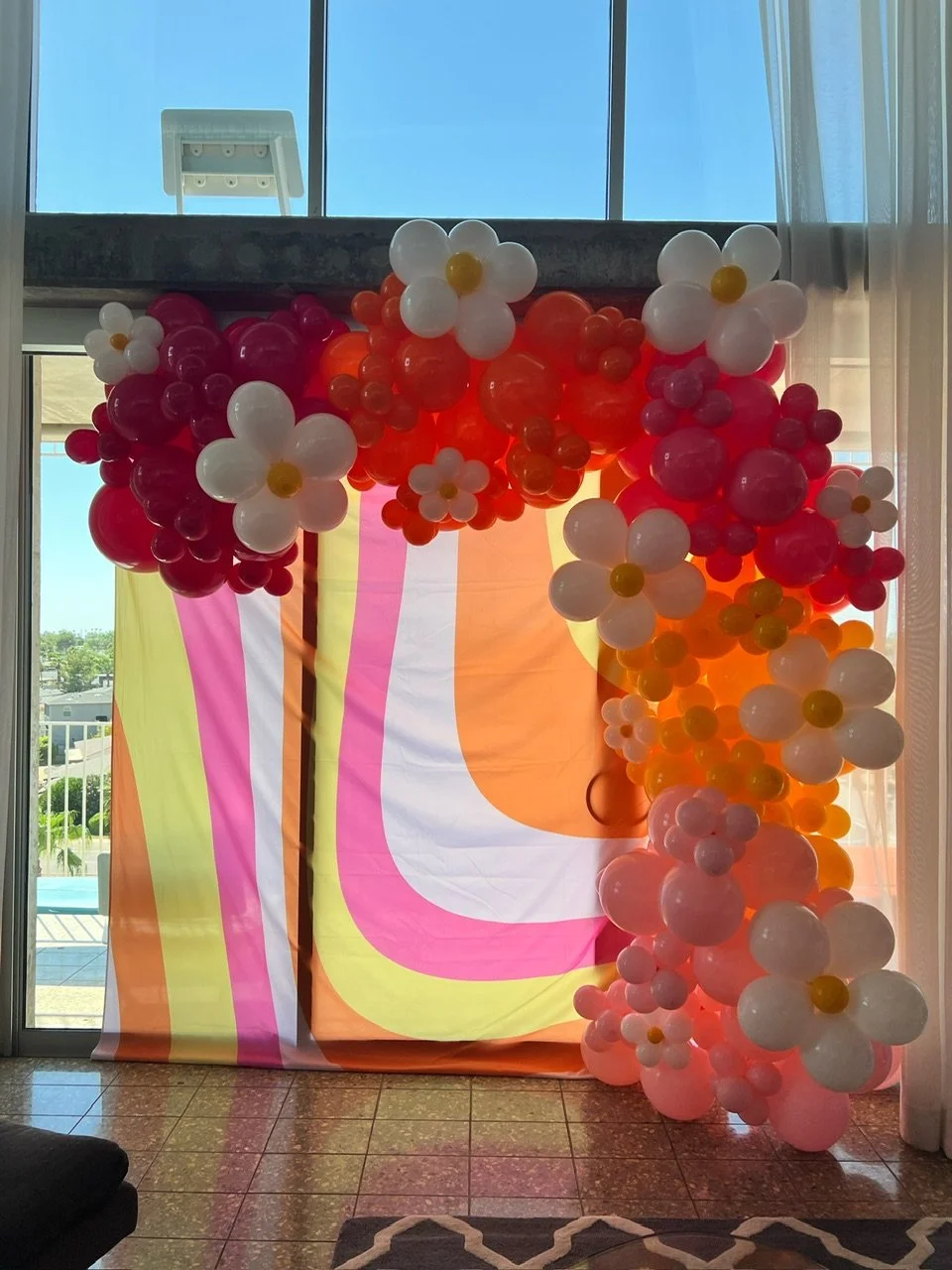 Luxury retro-themed bachelorette balloon installation by Pop by Dantana Design Co. serving Tacoma and Gig Harbor.  Features a vibrant orange, pink, and red organic garland with custom balloon daisies and a colorful backdrop.