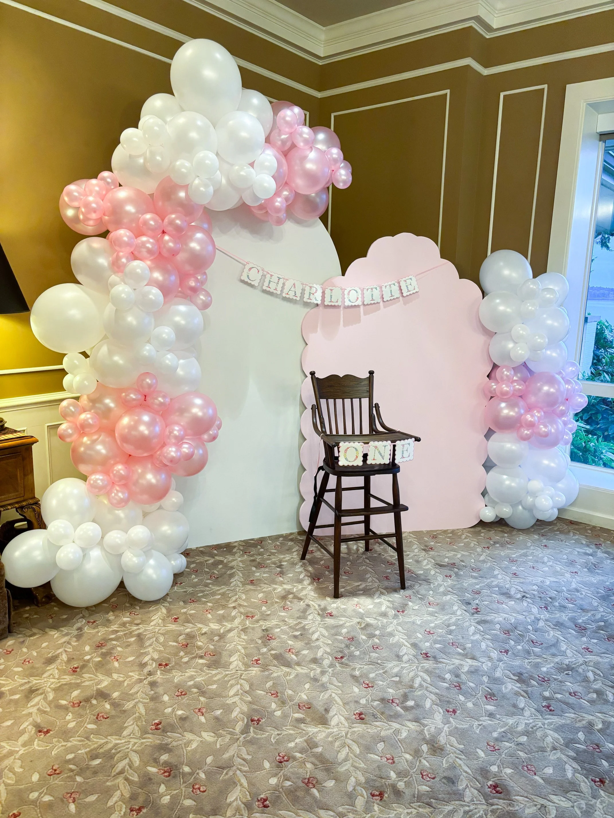 Custom first birthday balloon installation by Pop by Dantana Design Co. featuring a pink and white organic garland and scalloped backdrop for a celebration in Tacoma, WA.