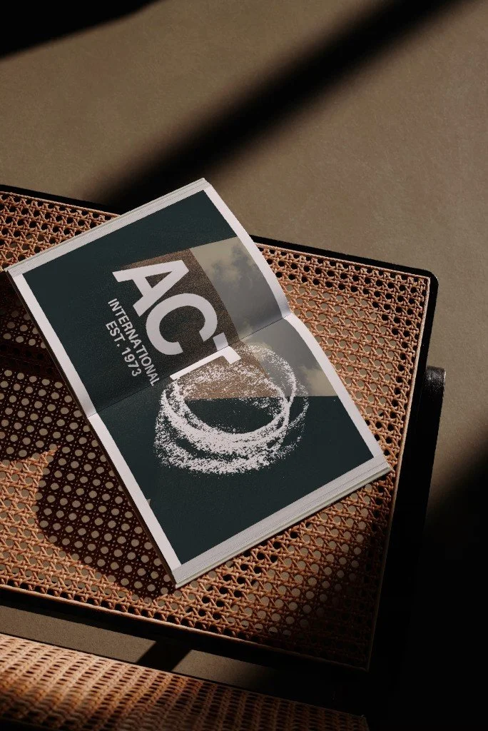 A booklet titled 'ACR International EST 1973' resting on a wicker chair.