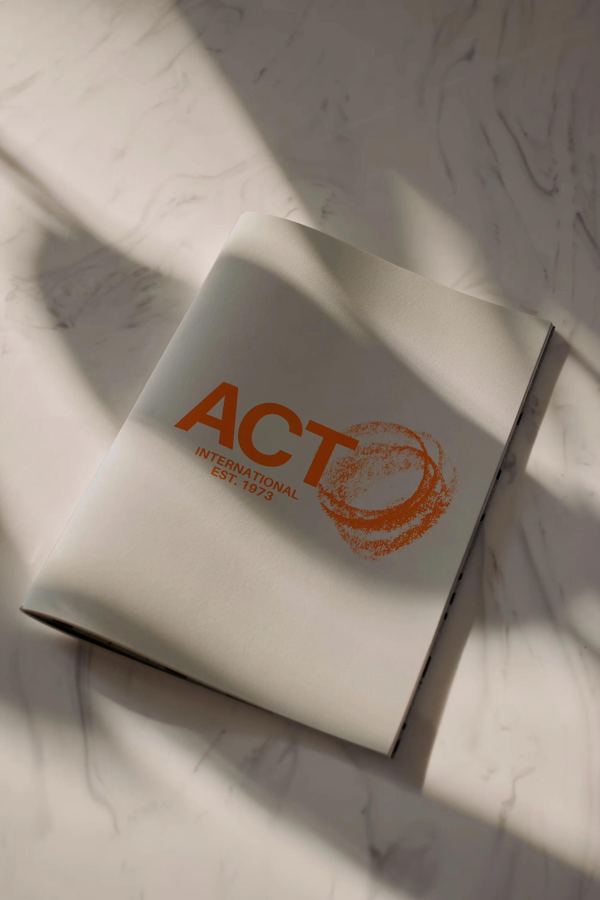 A magazine or brochure with the partially visible title 'ACT' and the subtitle 'International' on a white marble surface.