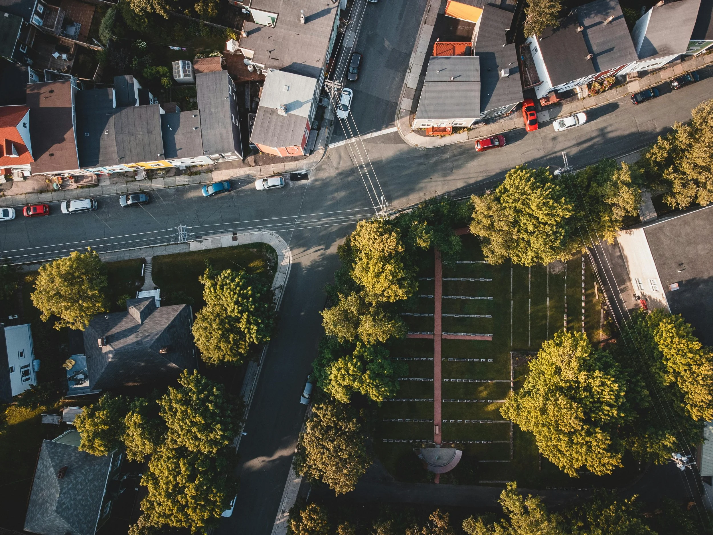 An aerial view of a residential neighborhood with houses, trees, and parked cars along the streets.