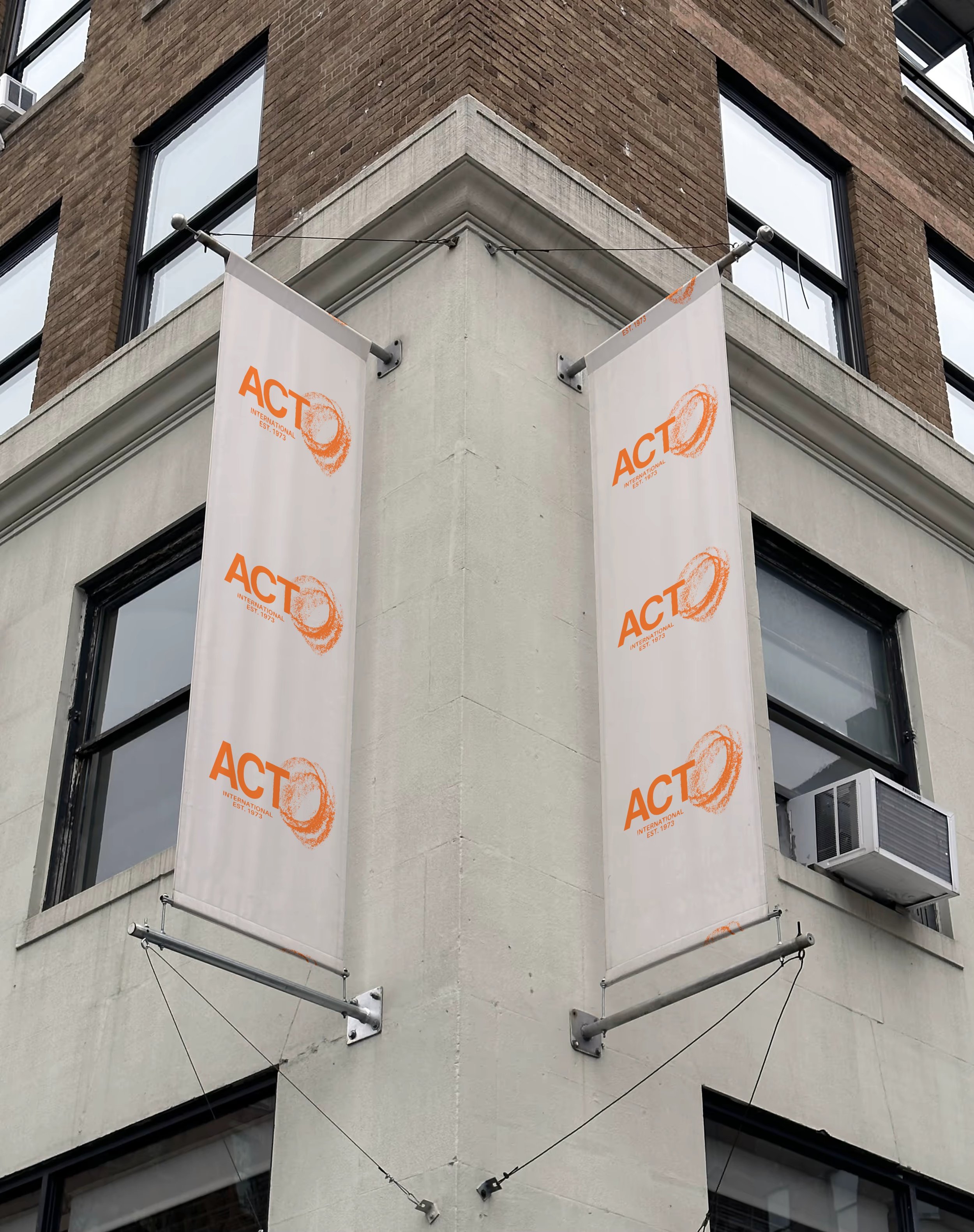 Banners hanging on a corner of a brick building displaying the ACT International logo and establishment year 1973.