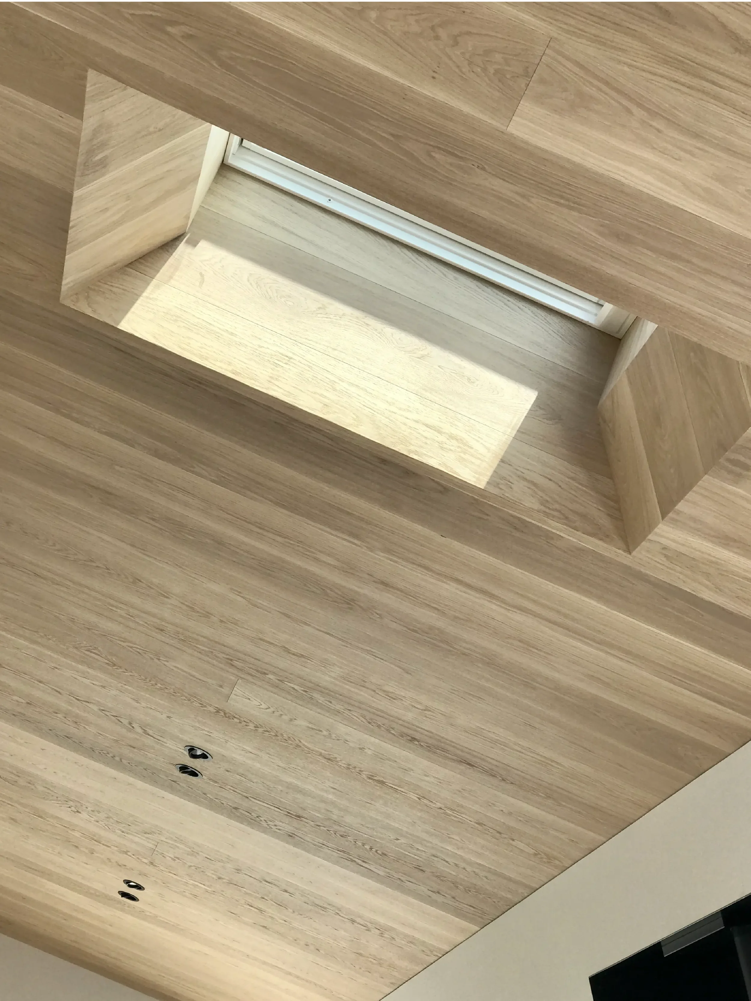Wooden ceiling with recessed lighting and two black electrical outlets.