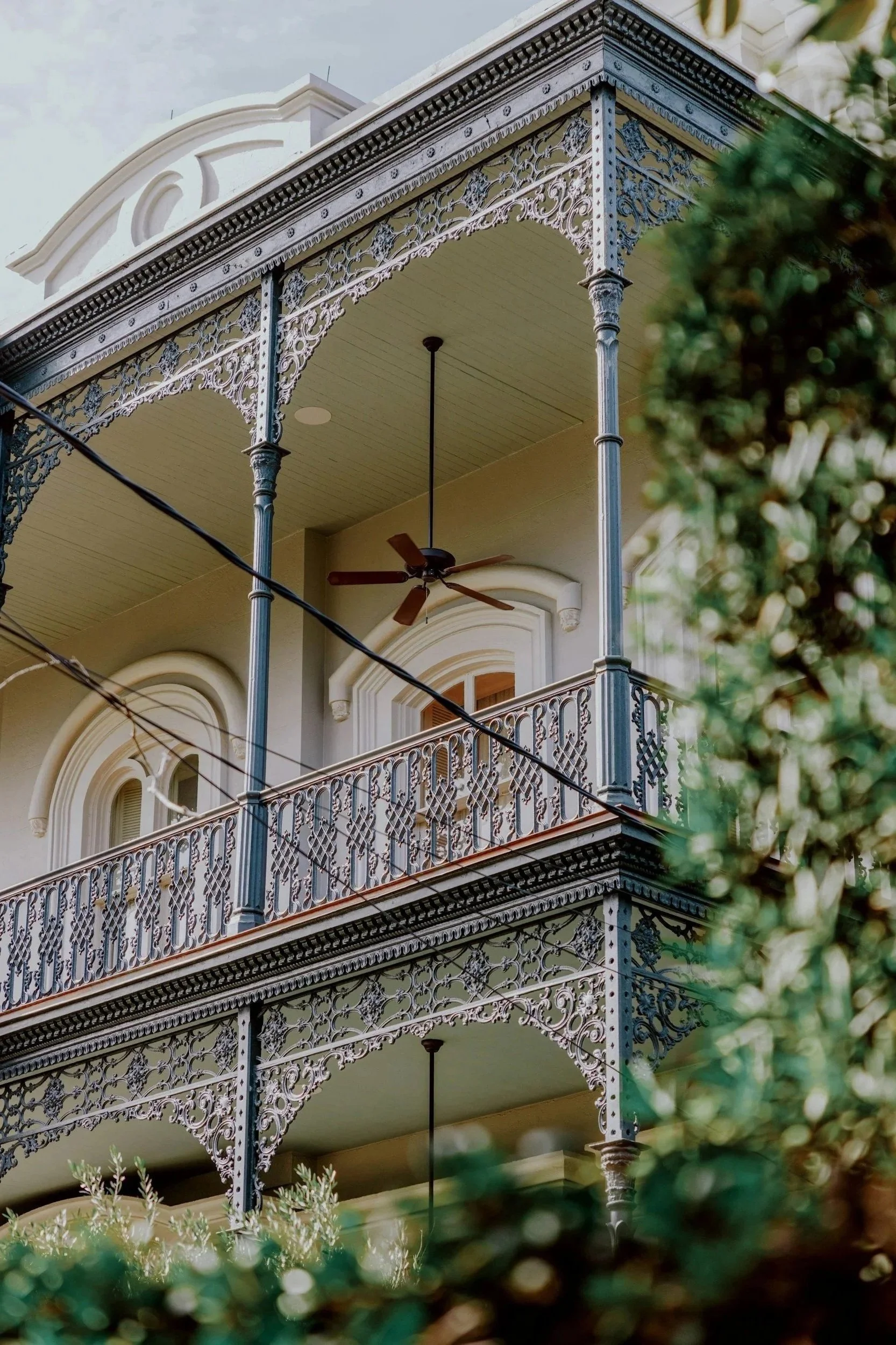 Historic New Orleans architectural detail featuring ornate iron balcony railings, arched windows, and timeless design elements highlighting classic residential redevelopment opportunities.