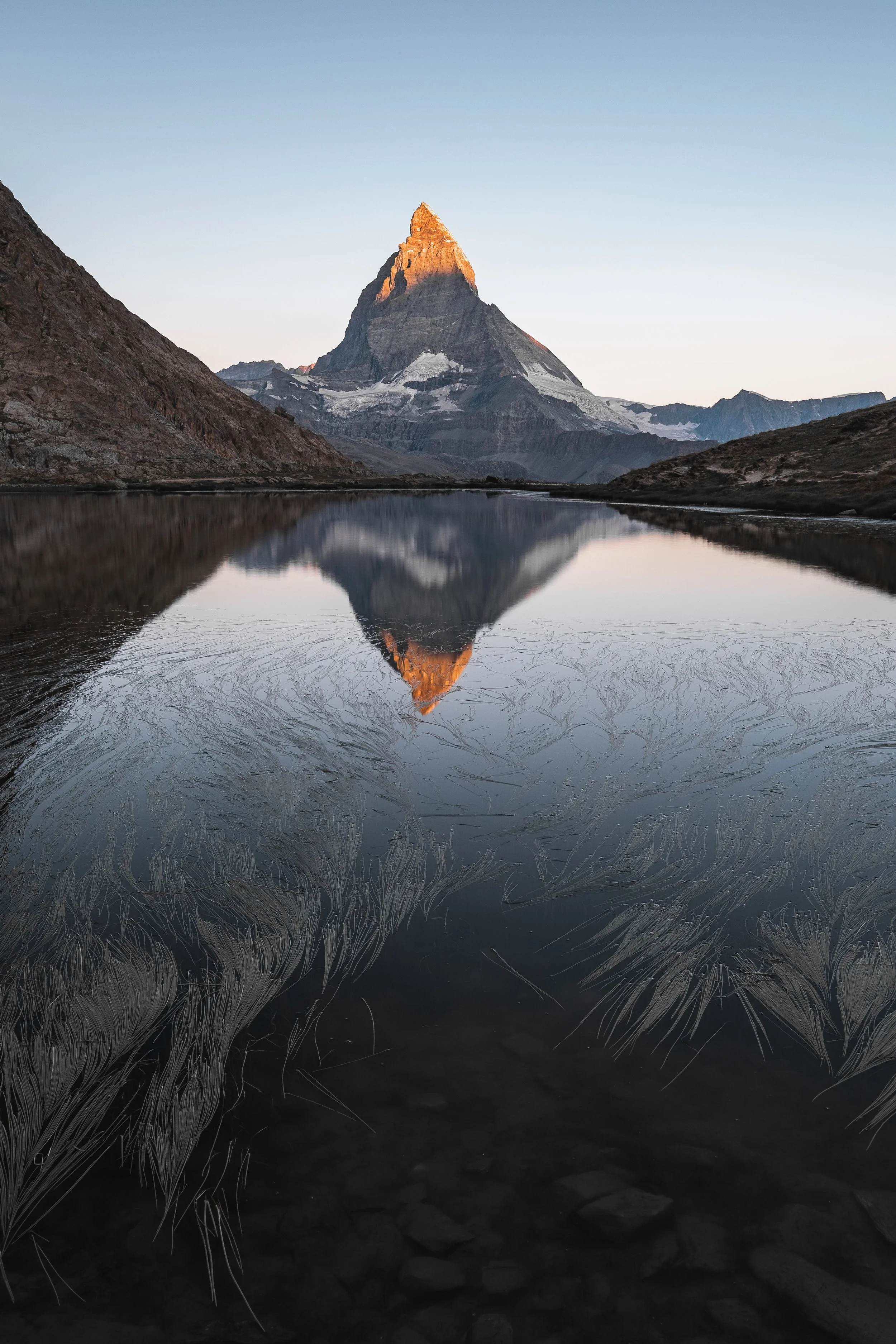 Das Matterhorn spiegelt sich im ruhigen Wasser des Riffelsees in der Morgenstunde.
