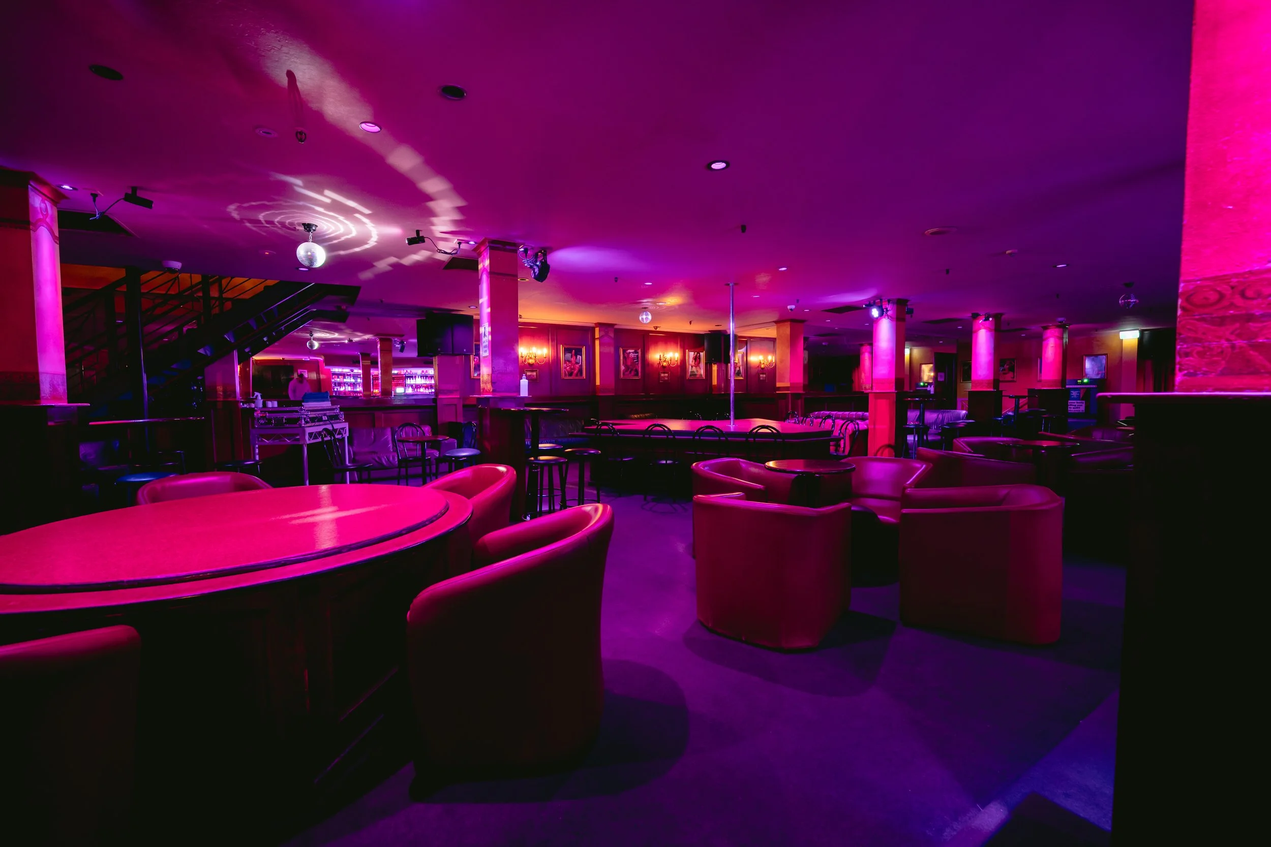 Round booth seating under purple lighting at The Men's Gallery Melbourne strip club