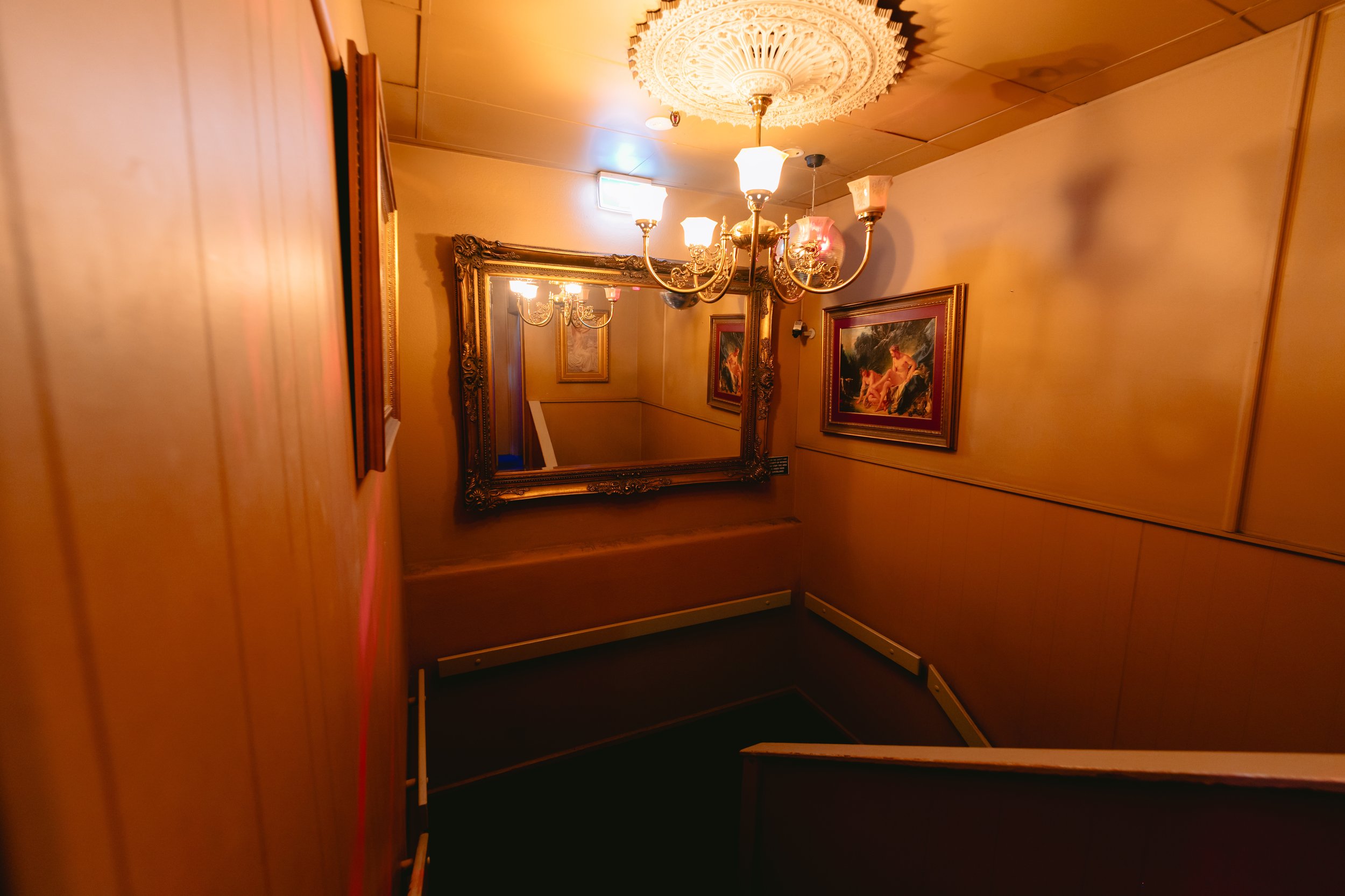 Elegant hallway with chandelier and framed art at The Men's Gallery Melbourne strip club