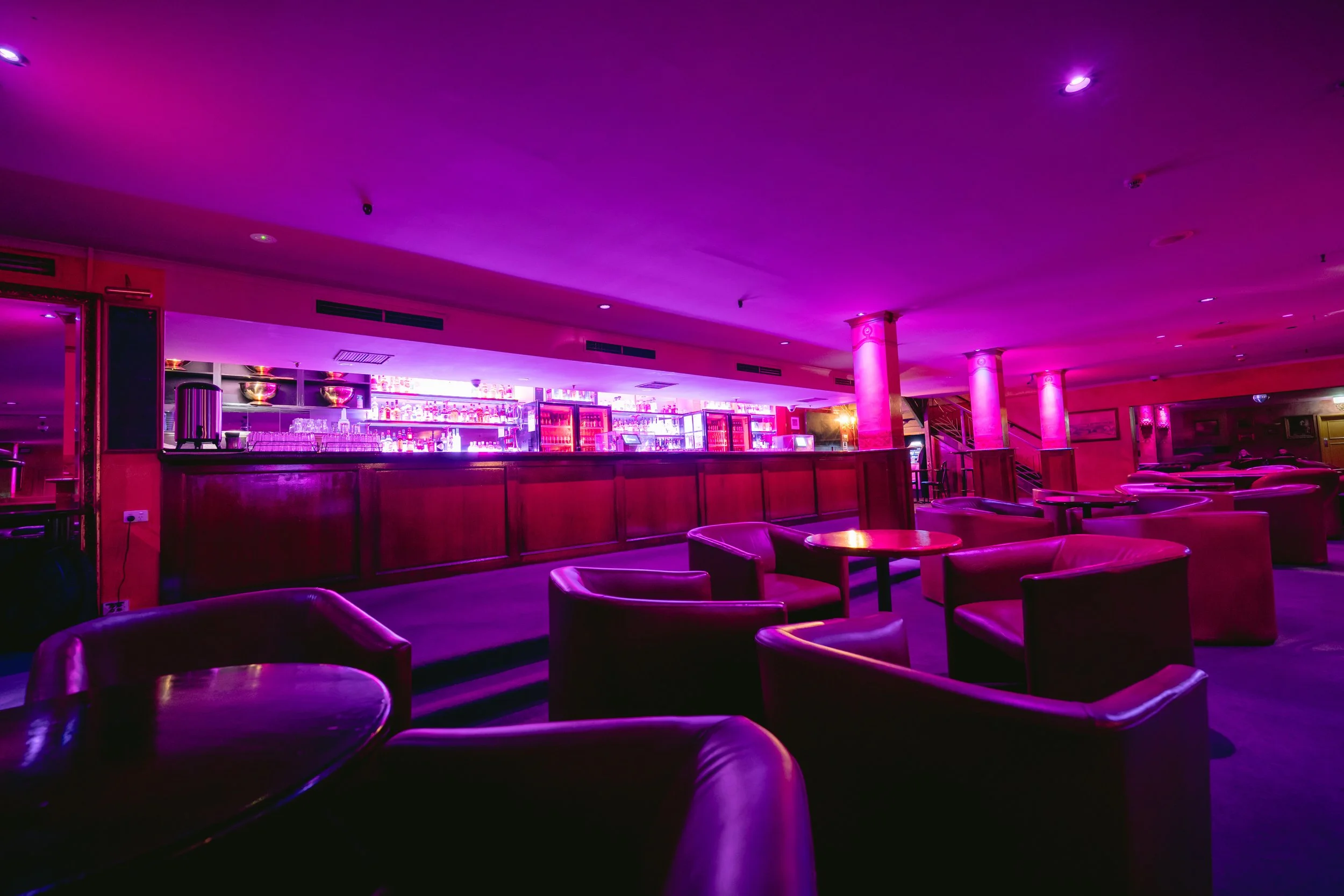 Bar and lounge seating under purple lighting at The Men's Gallery Melbourne strip club