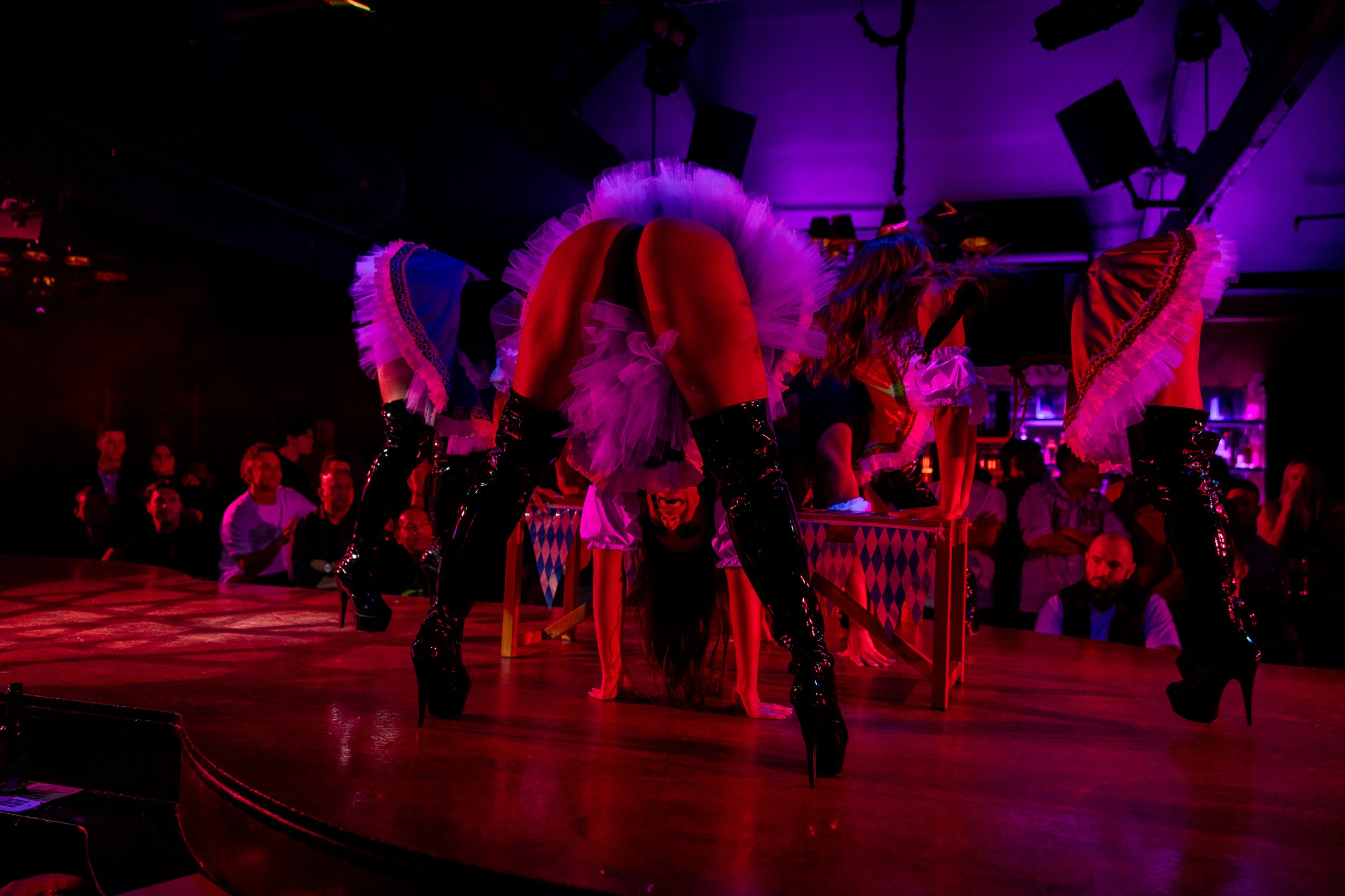 Group stage performers in feathered showgirl costumes during a feature show at The Men's Gallery Melbourne strip club