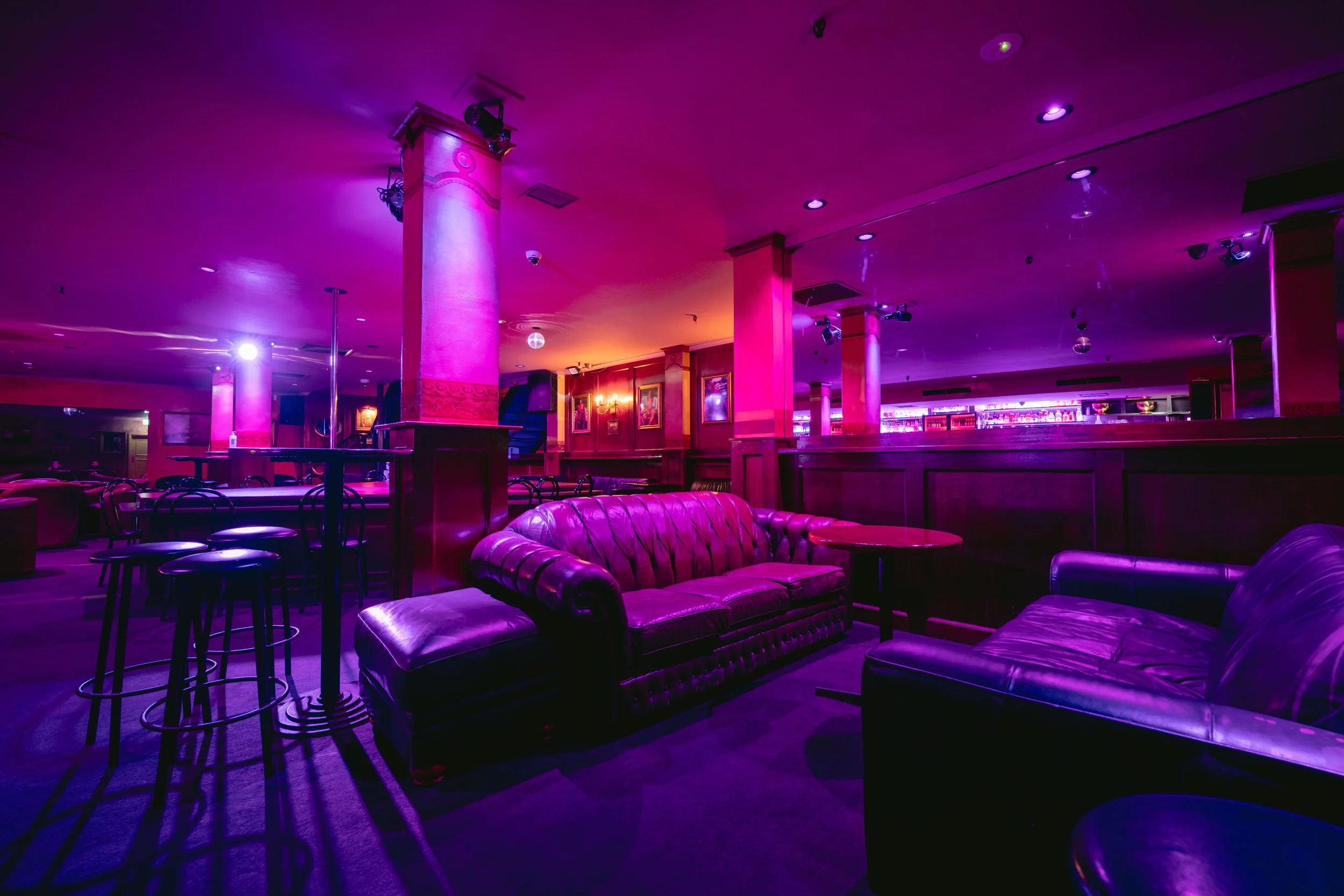 Pink-lit lounge seating area at The Men's Gallery Melbourne strip club