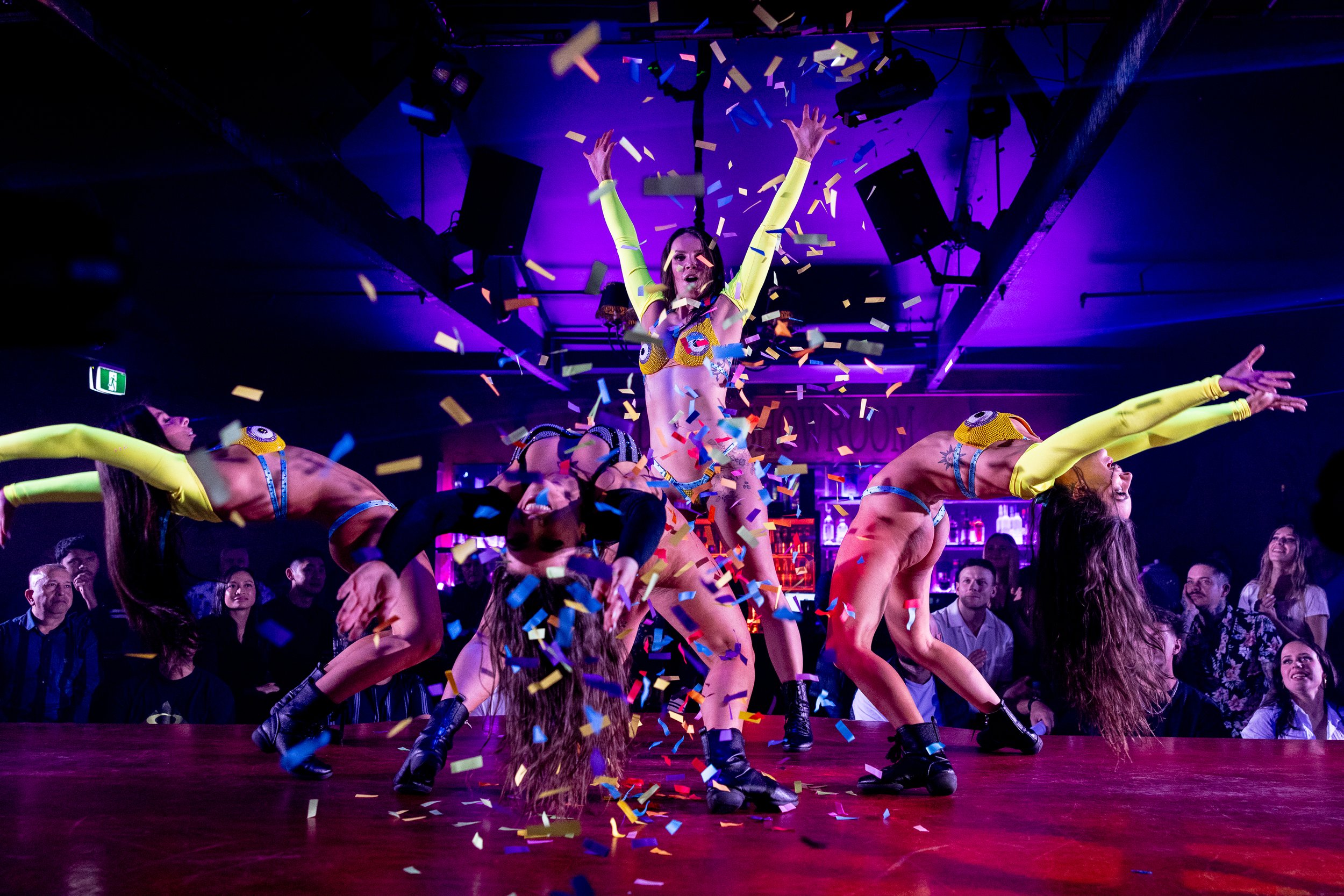 Group stage performers celebrating with confetti during a feature show at The Men's Gallery Melbourne strip club