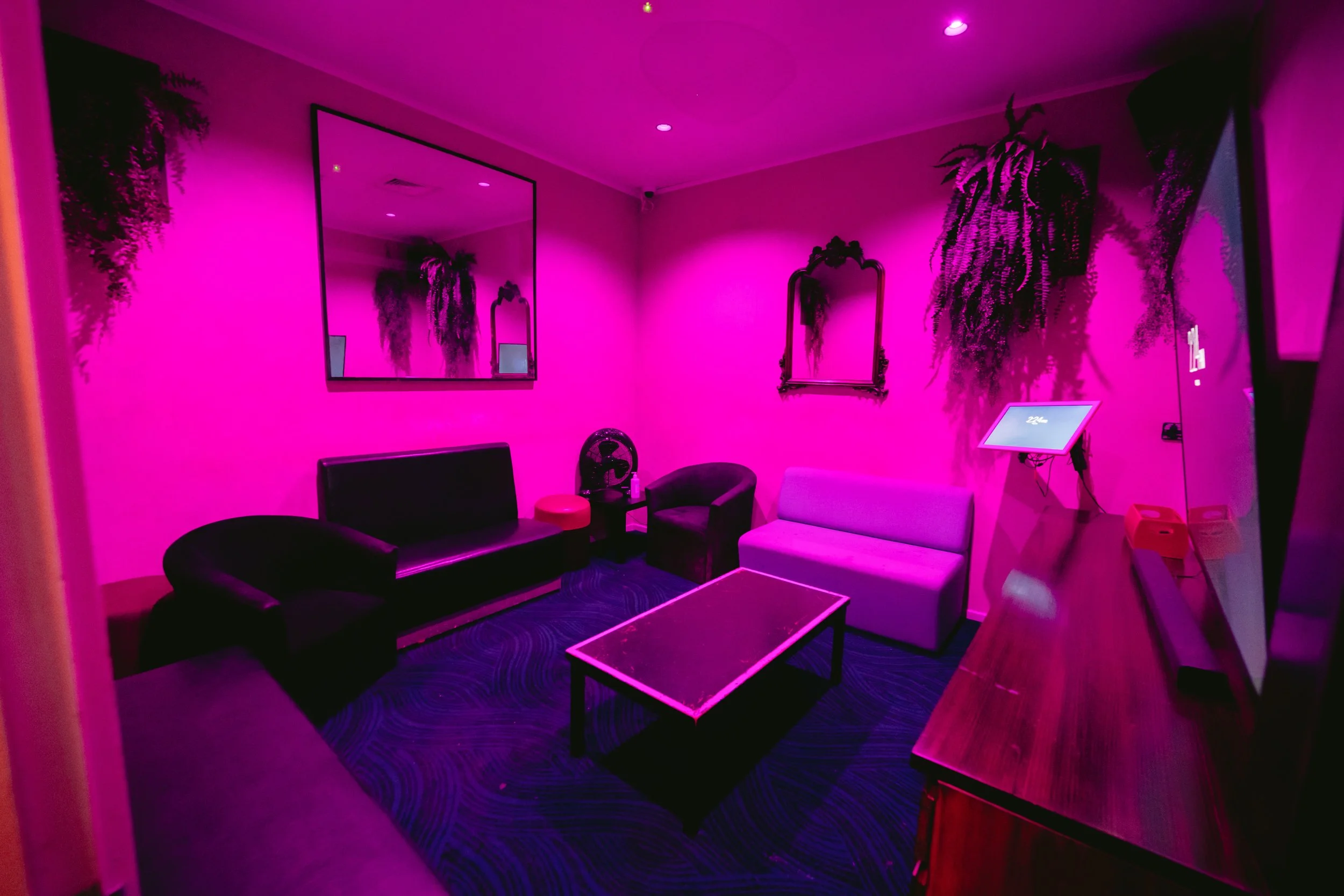Private lounge room with couches under pink lighting at The Men's Gallery Melbourne strip club