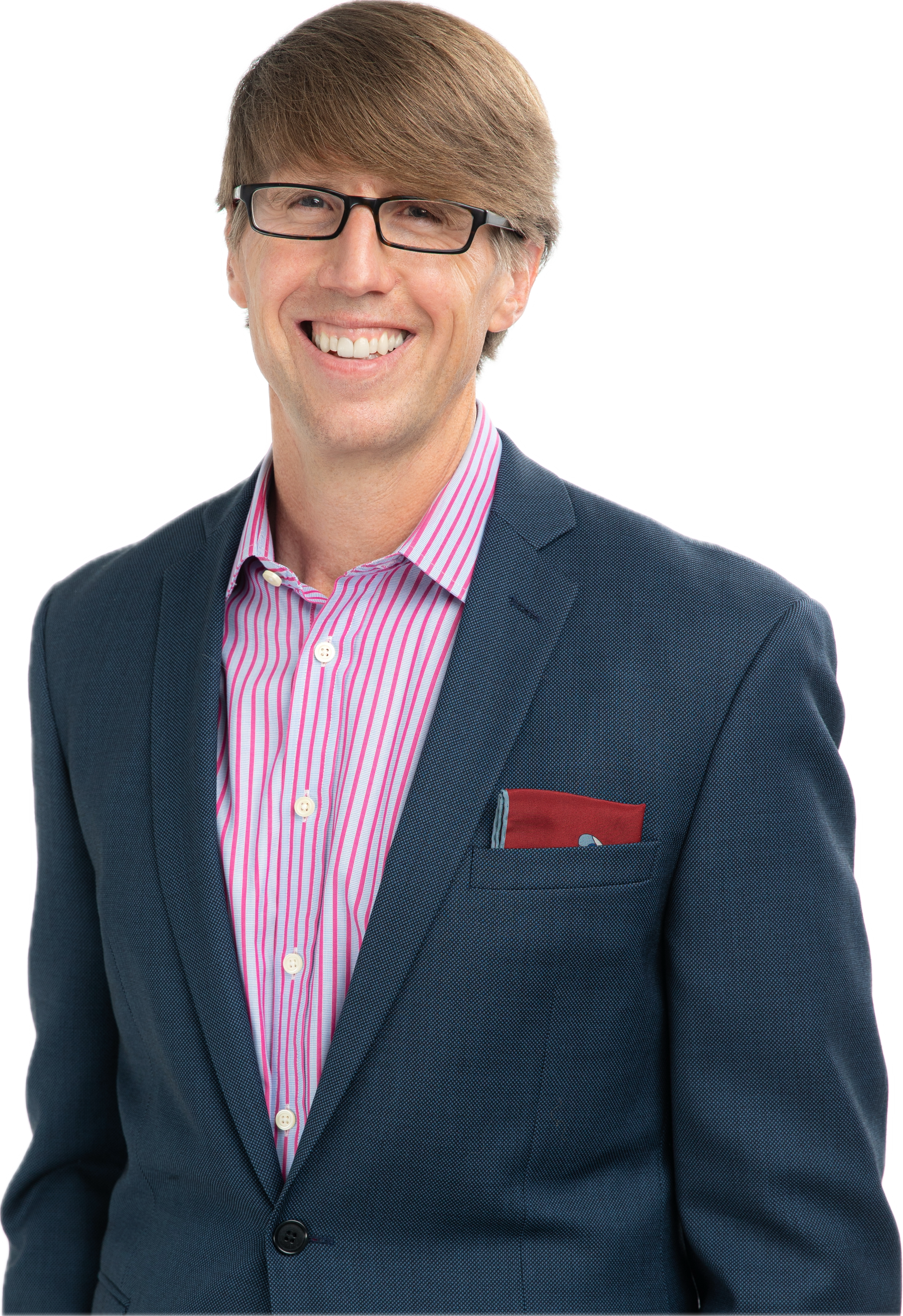 A smiling man in a navy blazer over a pink and white striped shirt, wearing glasses, with a red pocket square.