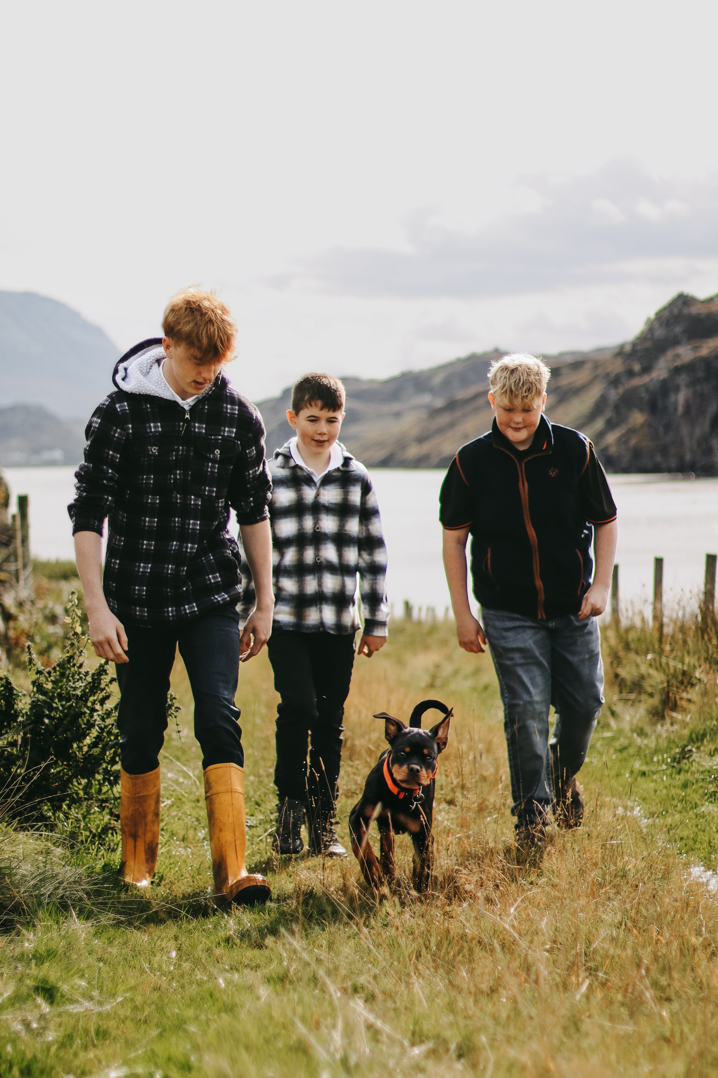 Family photography Scottish Highlands children walking with dog along coastal path in natural light