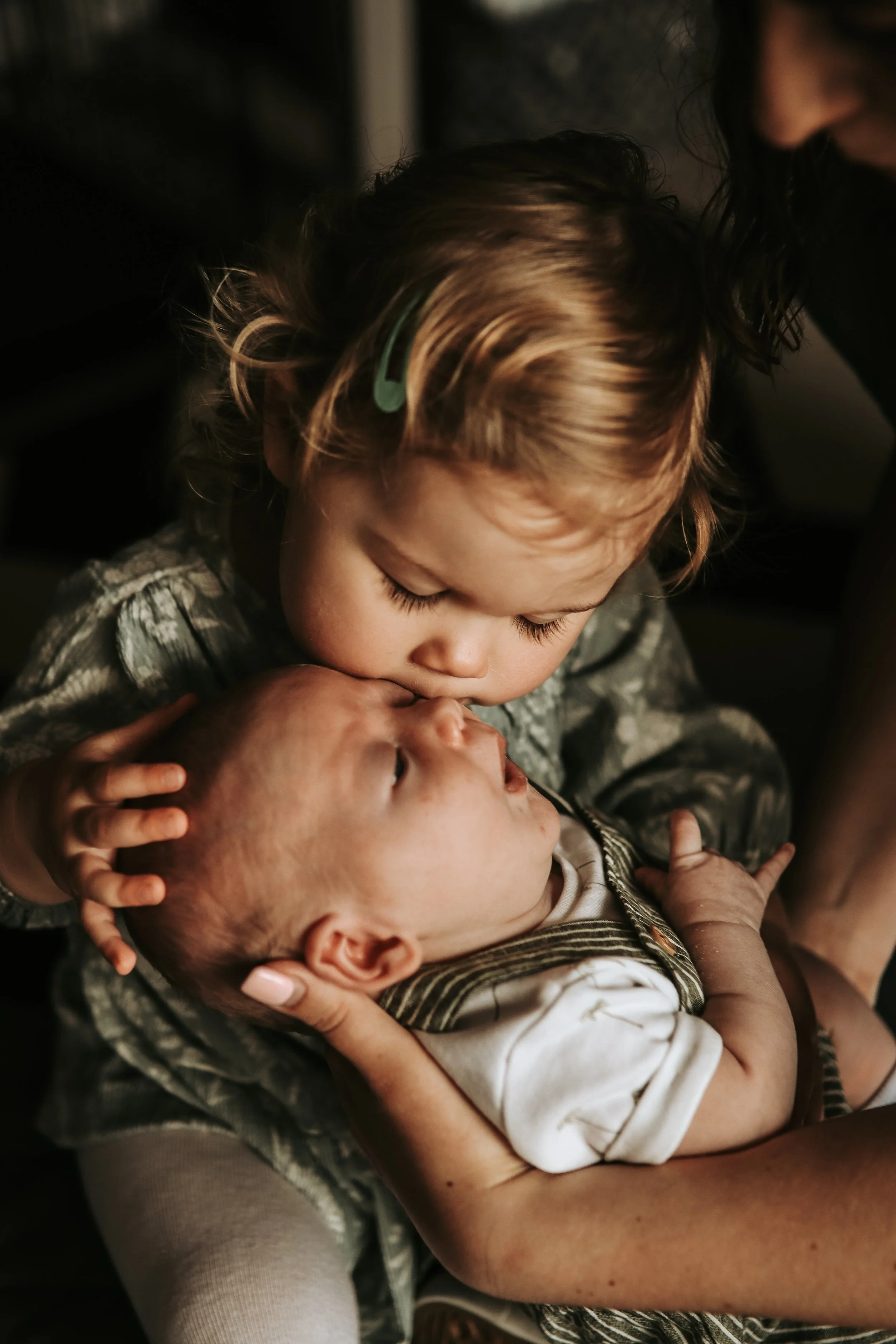 Lifestyle newborn photography Scottish Highlands sibling holding and kissing baby