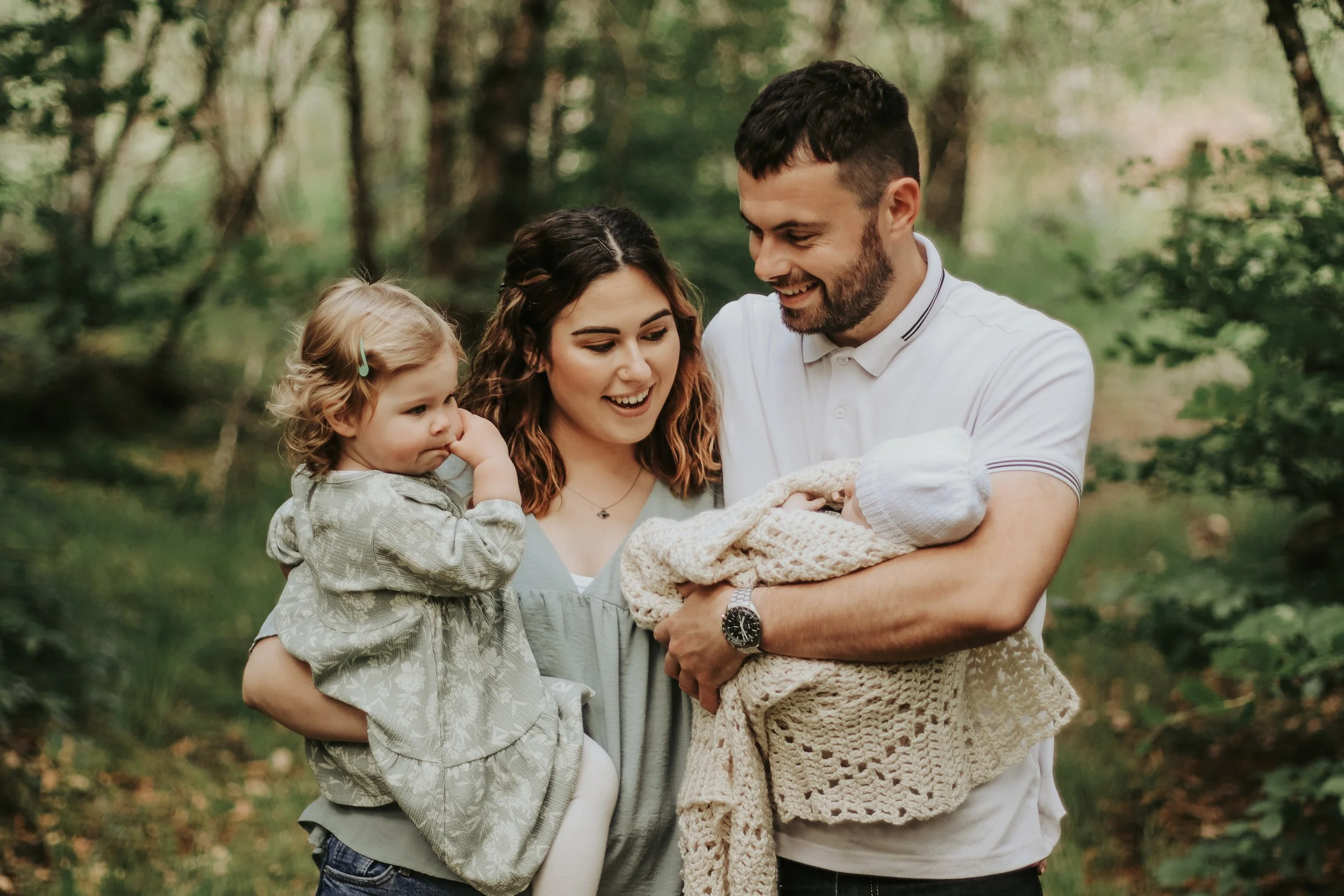 Family and newborn photography Scottish Highlands parents holding baby and toddler outdoors in natural light