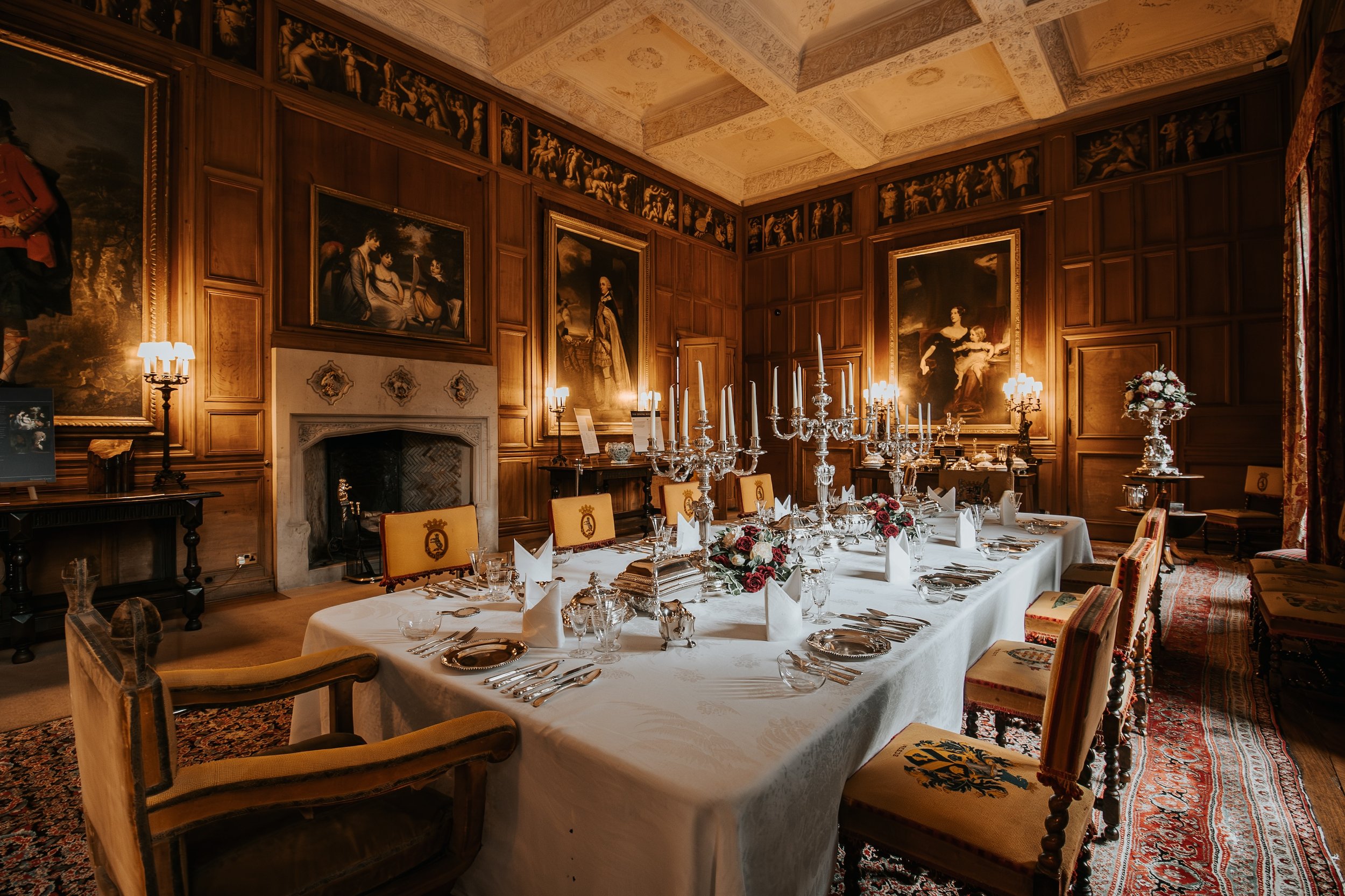 Interior photography of the historic dining room at Dunrobin Castle, featuring an elegantly laid dining table, silver candelabras and grand portraits.