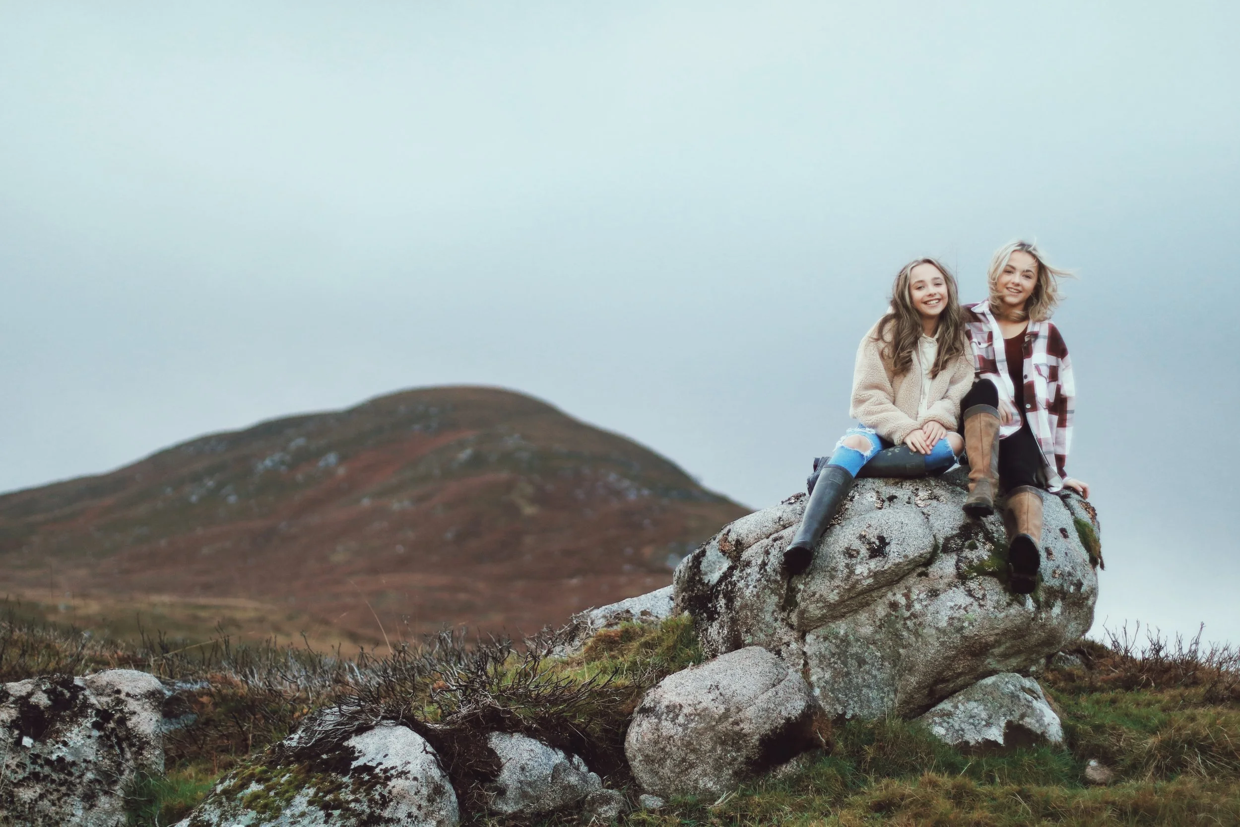 Family photography Sutherland Scottish Highlands children sitting on rocks in mountain landscape natural light