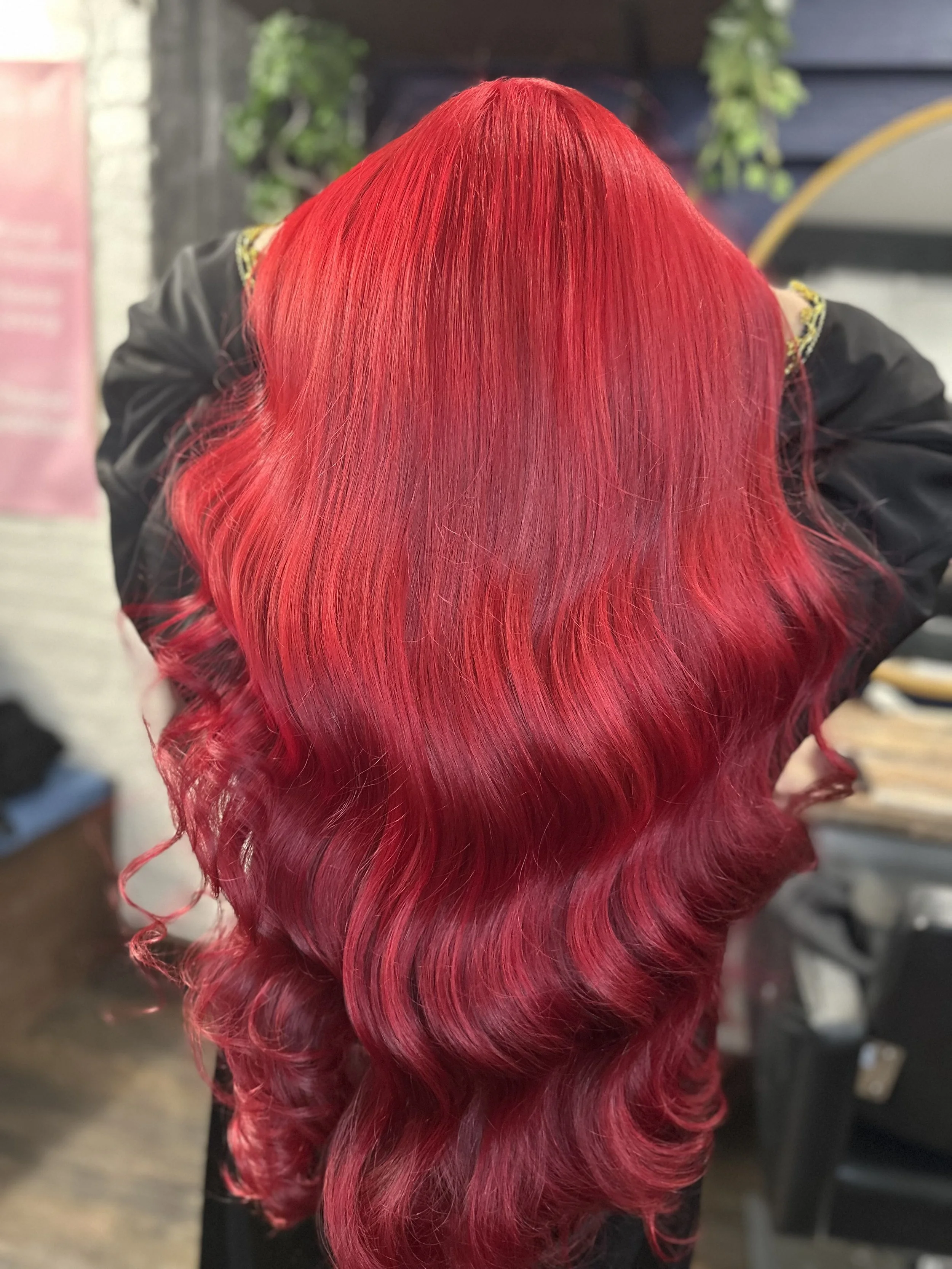 Side view of a person with long, vibrant red hair styled in loose curls.