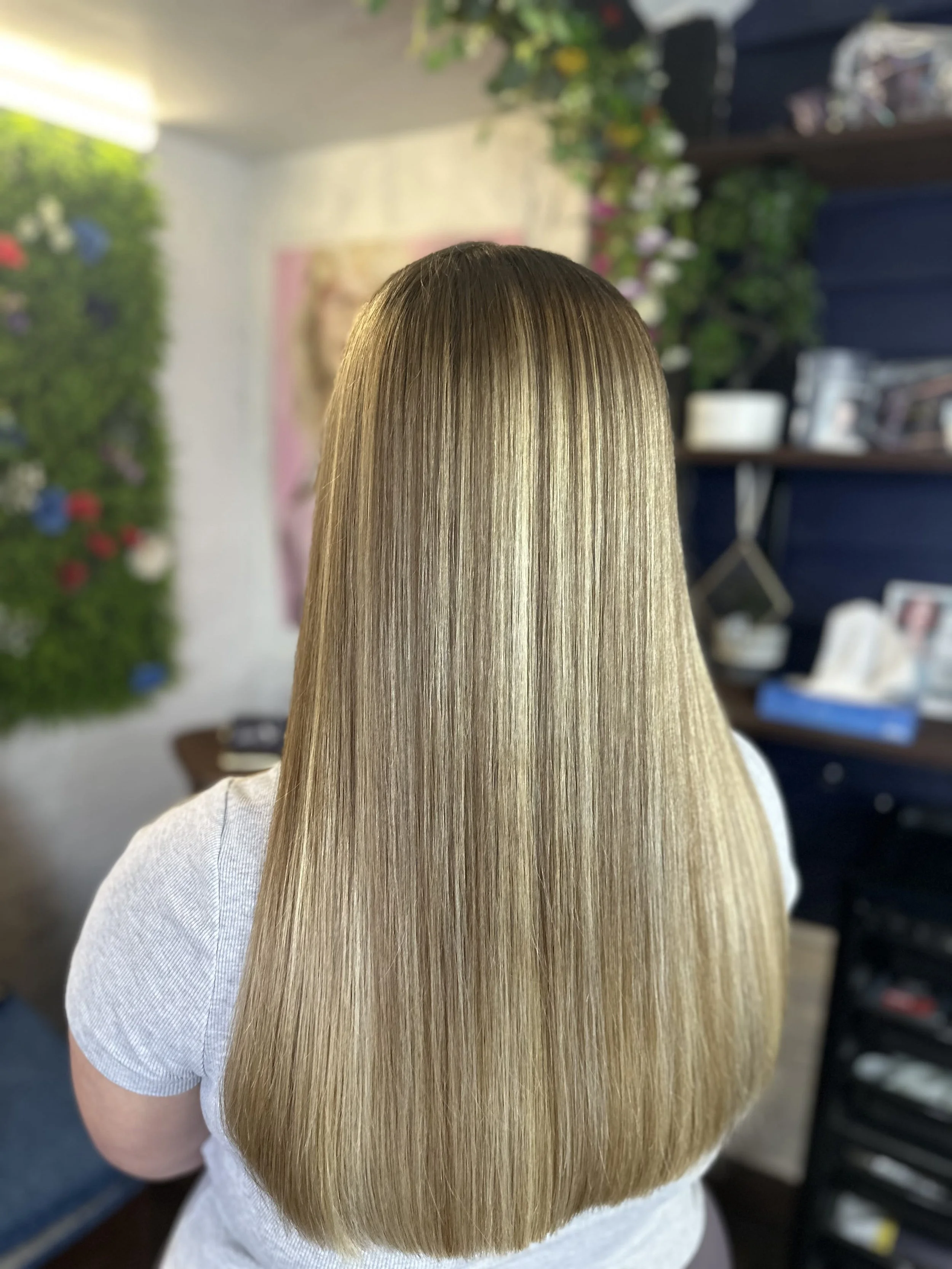 Person with long, straight, blonde hair in a salon or studio setting.