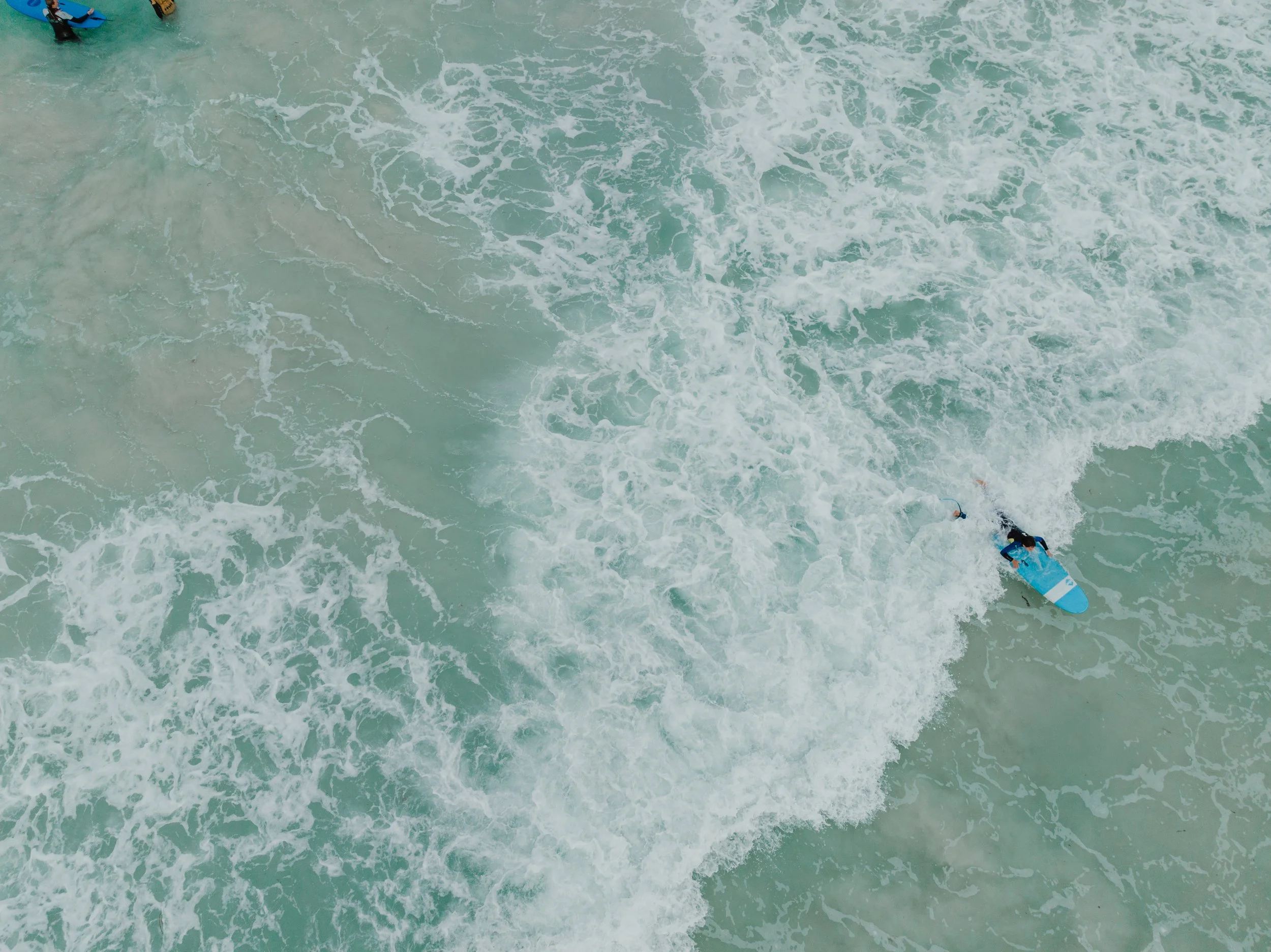 An aerial view of a person on a surfboard, riding a wave in the ocean.