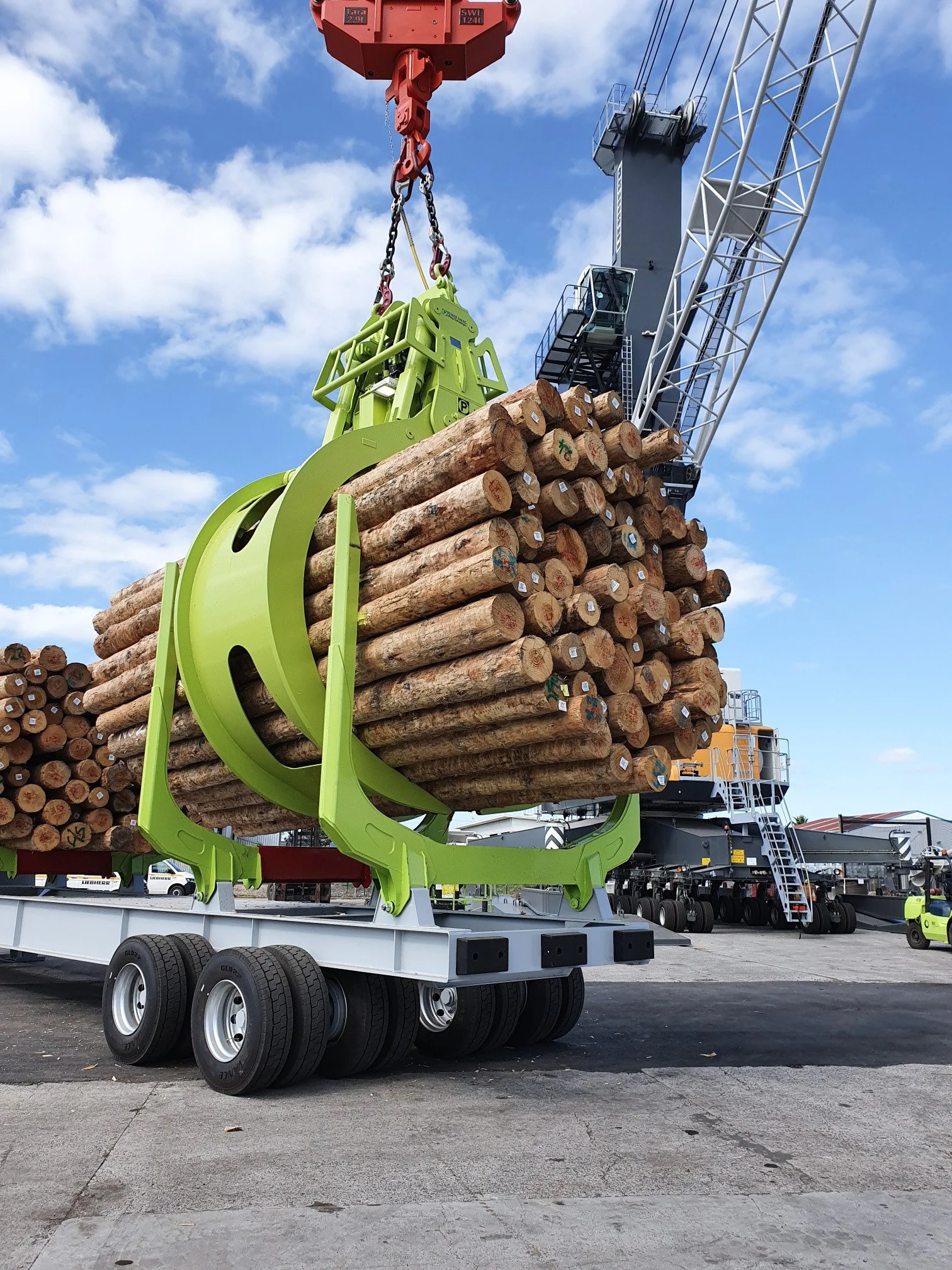 LKW mit hohem Holzstapel auf Ladefläche, mit Kran zum Be- und Entladen.