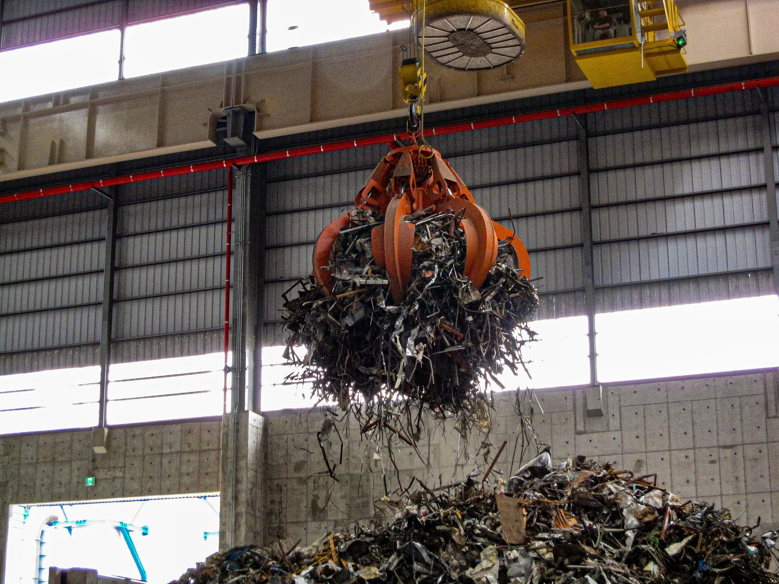 Großer Greifer in einer Recyclinganlage hebt eine große Menge Metallschrott.
