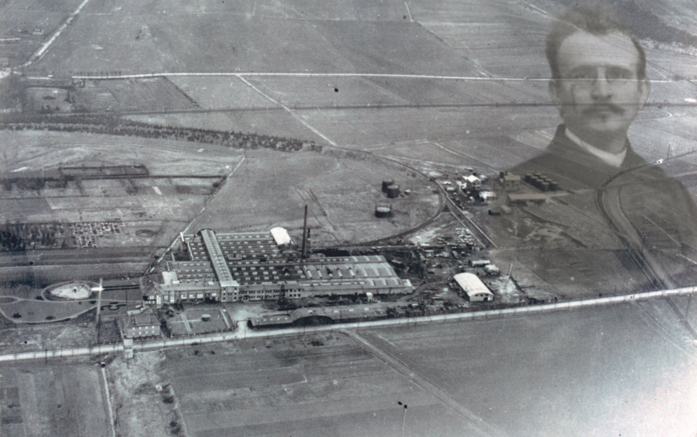 Schwarz-Weiß-Foto, das eine Stadt mit Straßen, Gebäuden und einer Person im Vordergrund zeigt.
