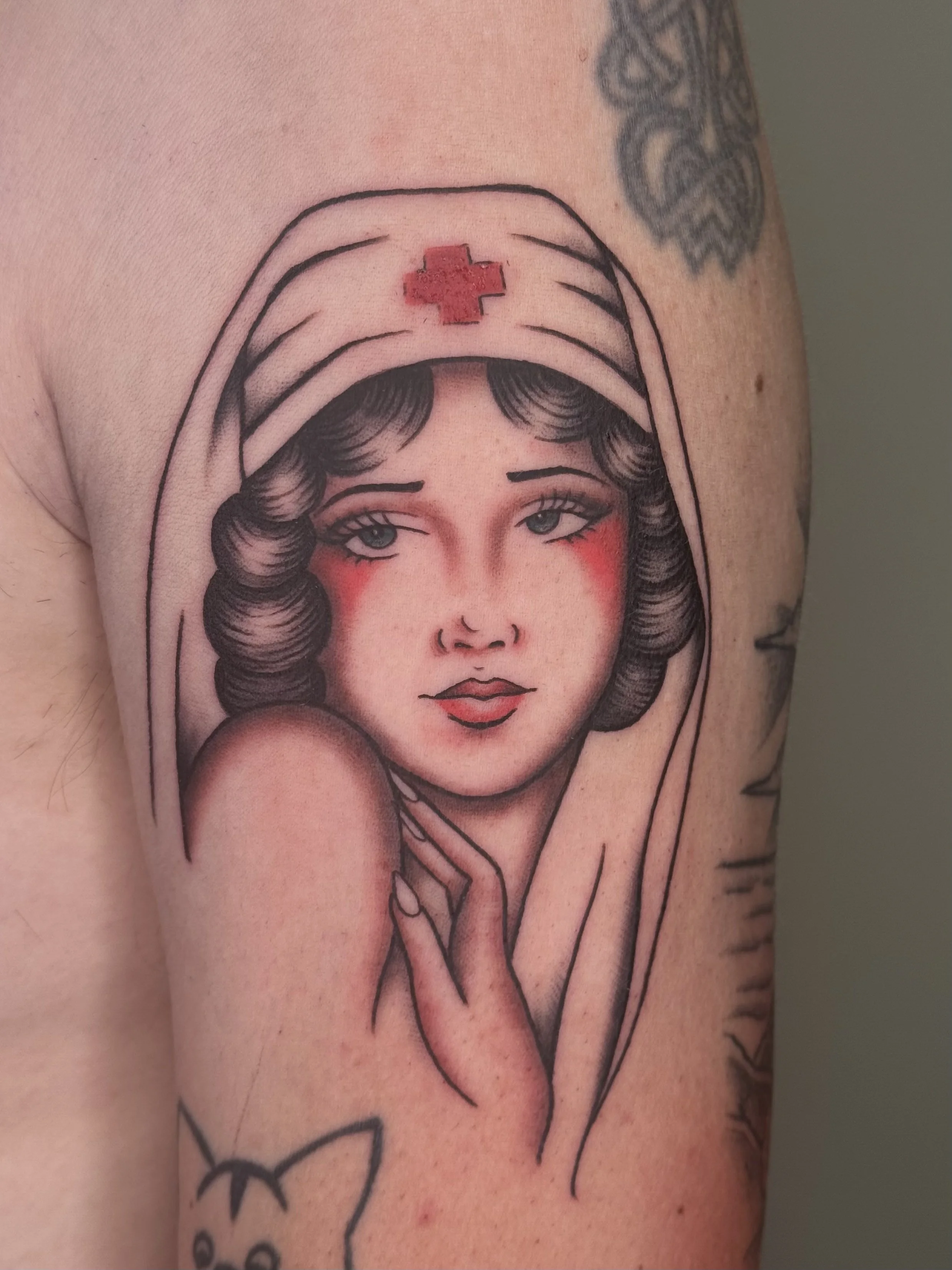 Tatoeage van een vrouw met halflange haar, blush op haar wangen, die een verpleegstershoed met een rood kruis draagt.