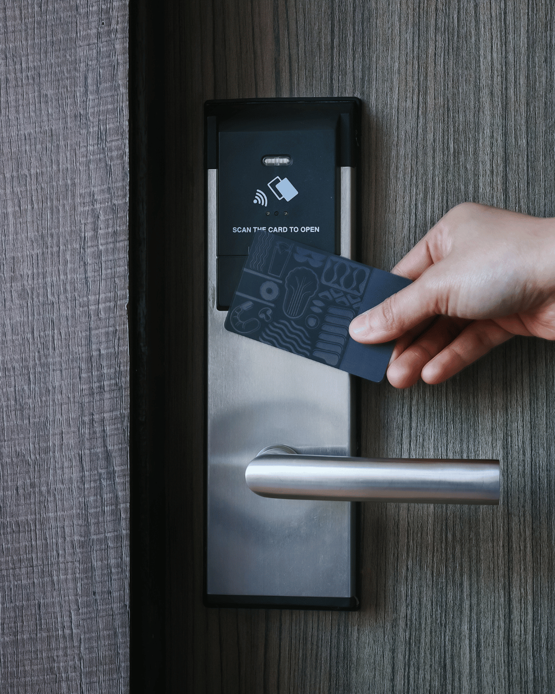 Person holding a contactless credit card near a door lock for access.
